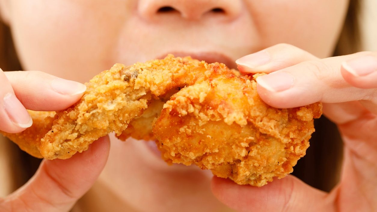 close up focus woman hand hold fried chicken for eat,girl with fast food concept