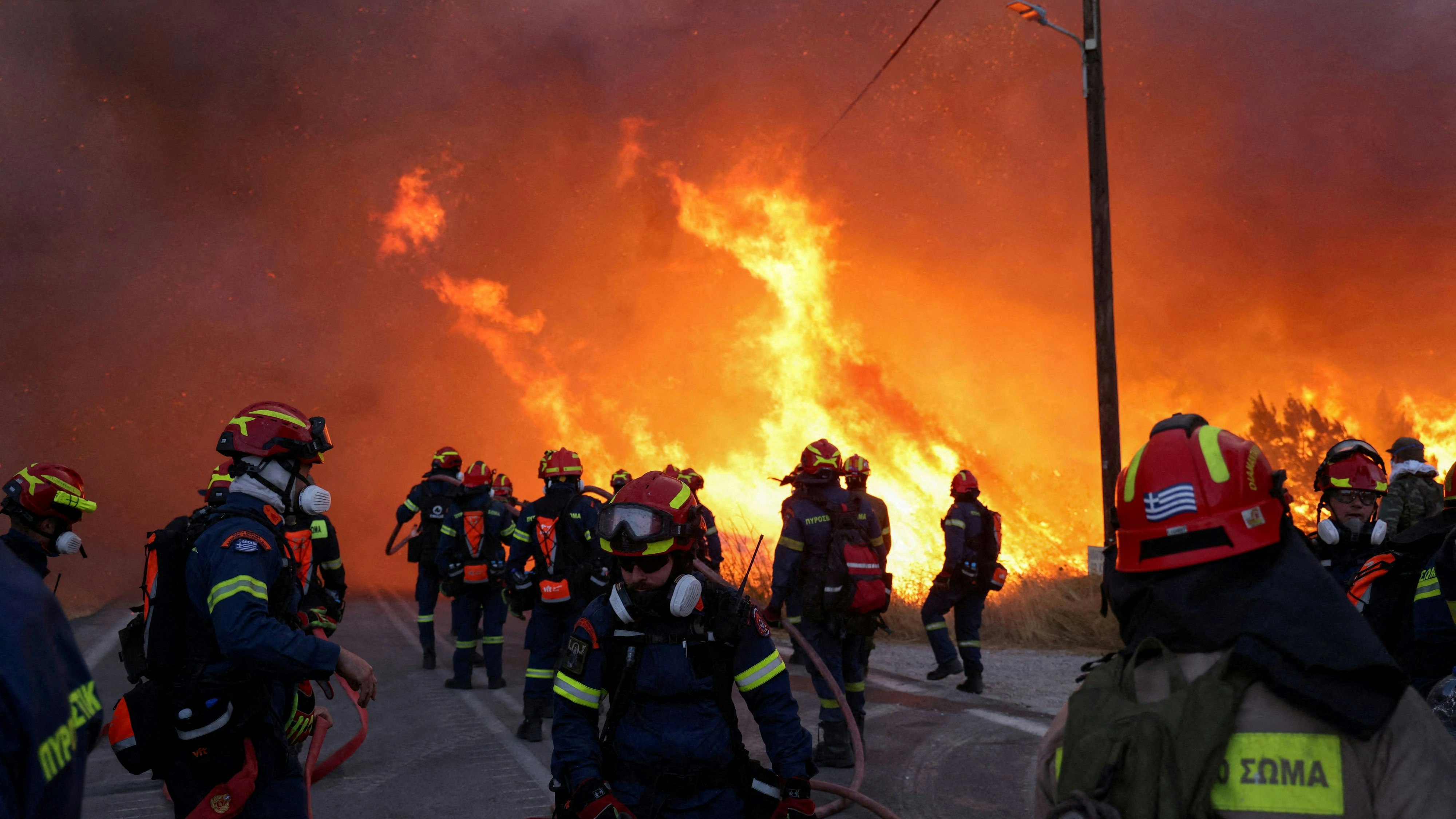 Firemen work to extinguish a wildfire, fanned by strong winds, which led to evacuation messages near the village of Karyes on Chios island, Greece, June 22, 2025. REUTERS/Kostas Anagnostou     TPX IMAGES OF THE DAY     