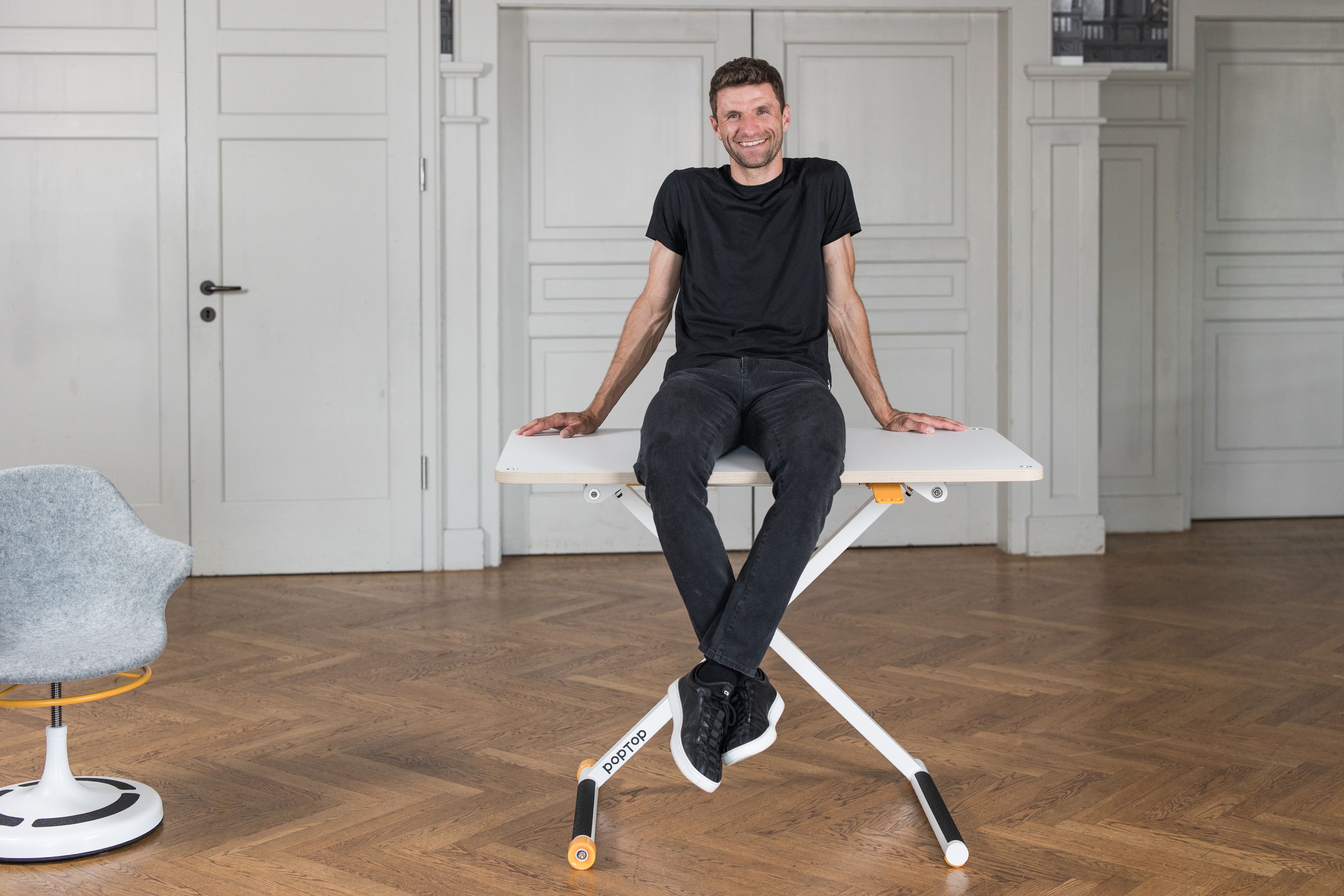 Thomas Müller sitzt auf dem Kinderschreibtisch von 