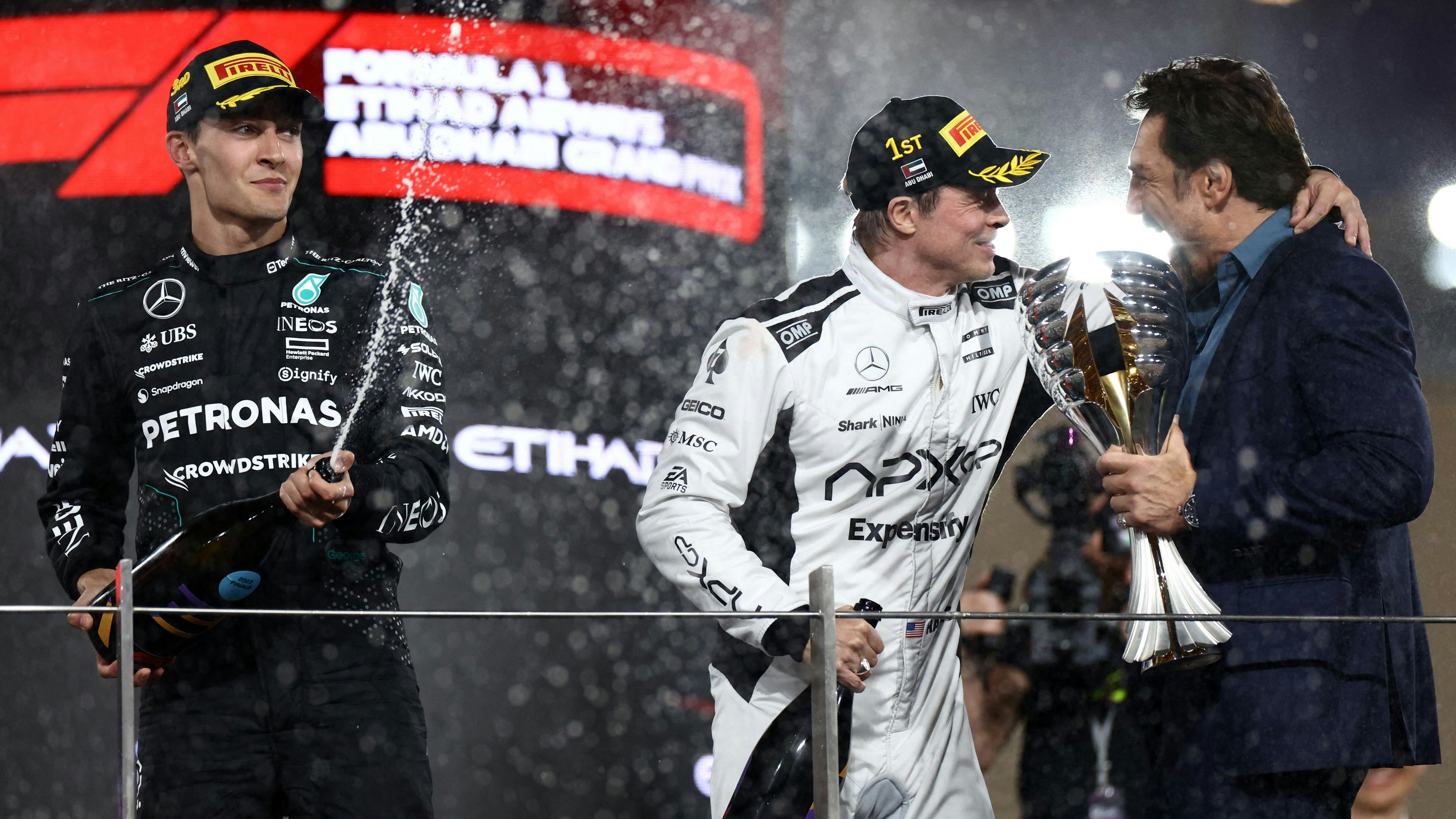 "Comeback-Kid" Sonny Hayes (Brad Pitt, Mitte) herzt seinen Teamchef Ruben Cervantes (Javier Bardem), während der echte Formel 1-Fahrer George Russell schon feiert