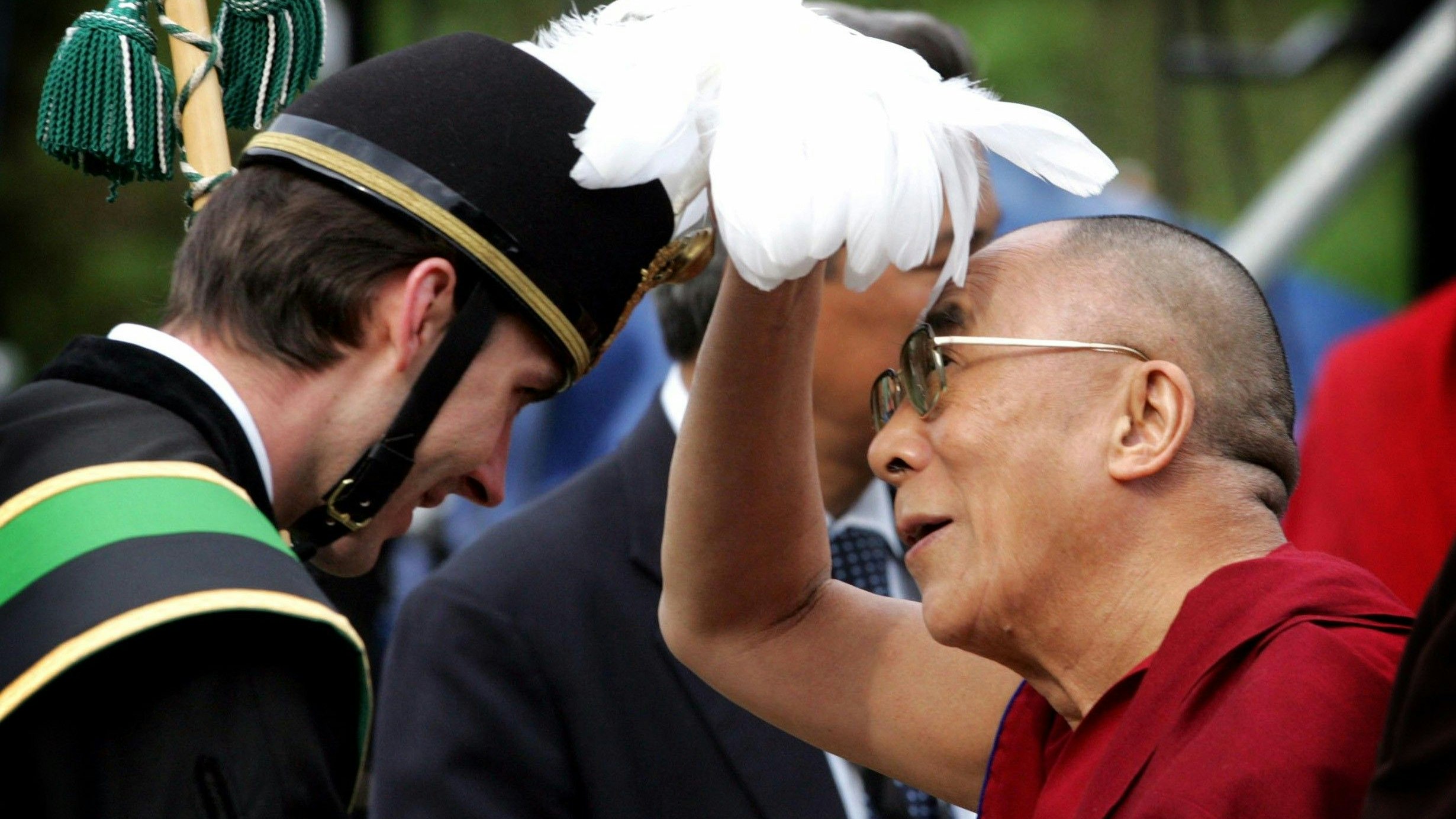 Der Dalai Lama inspiziert bei einem Besuch im Kärntner Hüttenberg 2006 den Federschmuck eines Knappen