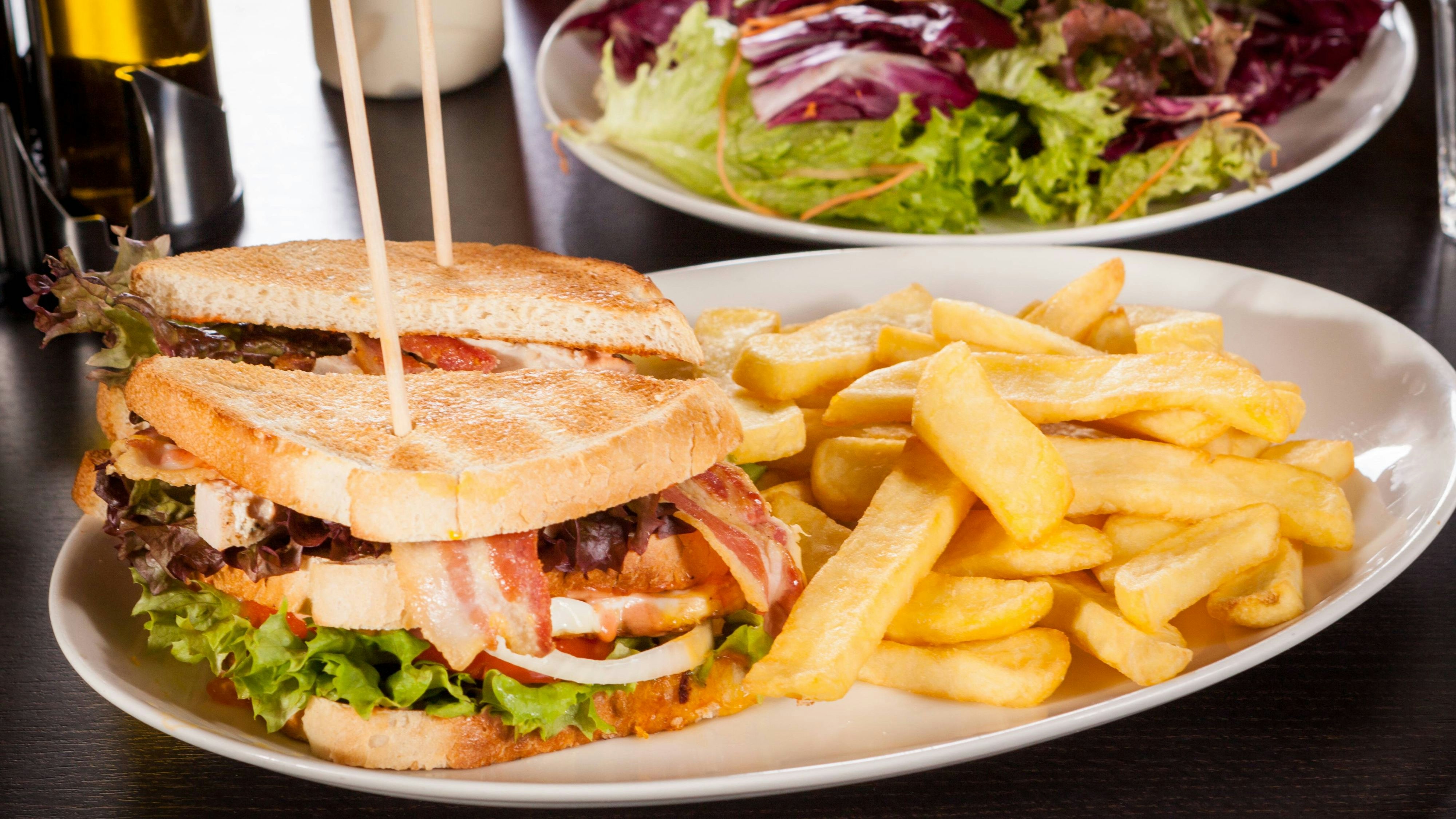 Clubsandwich auf getoastetem Weißbrot mit Speck und Pommes frittes Fritten auf einem Teller  Club sandwich on toasted White bread with Speck and French fries Frittes Frits on a Plate