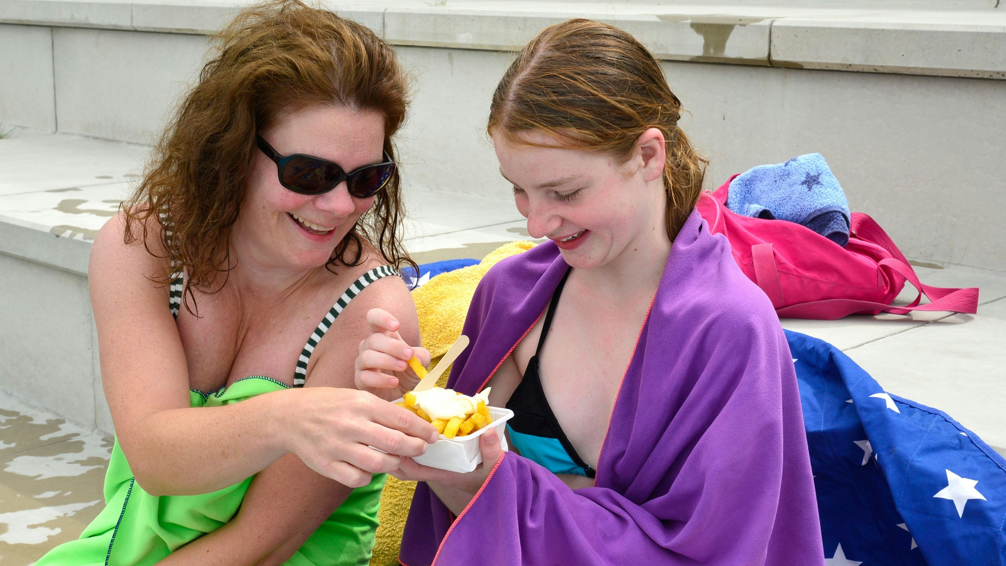 Frieda (10) mit Mama Jessica genießen eine Pommes. Disco-Sound im Freibad mit DJ Sven Kadelka aus Gevelsberg an der Bleichwiese  in Sprockhövel am Samstag, 09. Juli 2022. Foto: Barbara Zabka /  FUNKE Foto Services