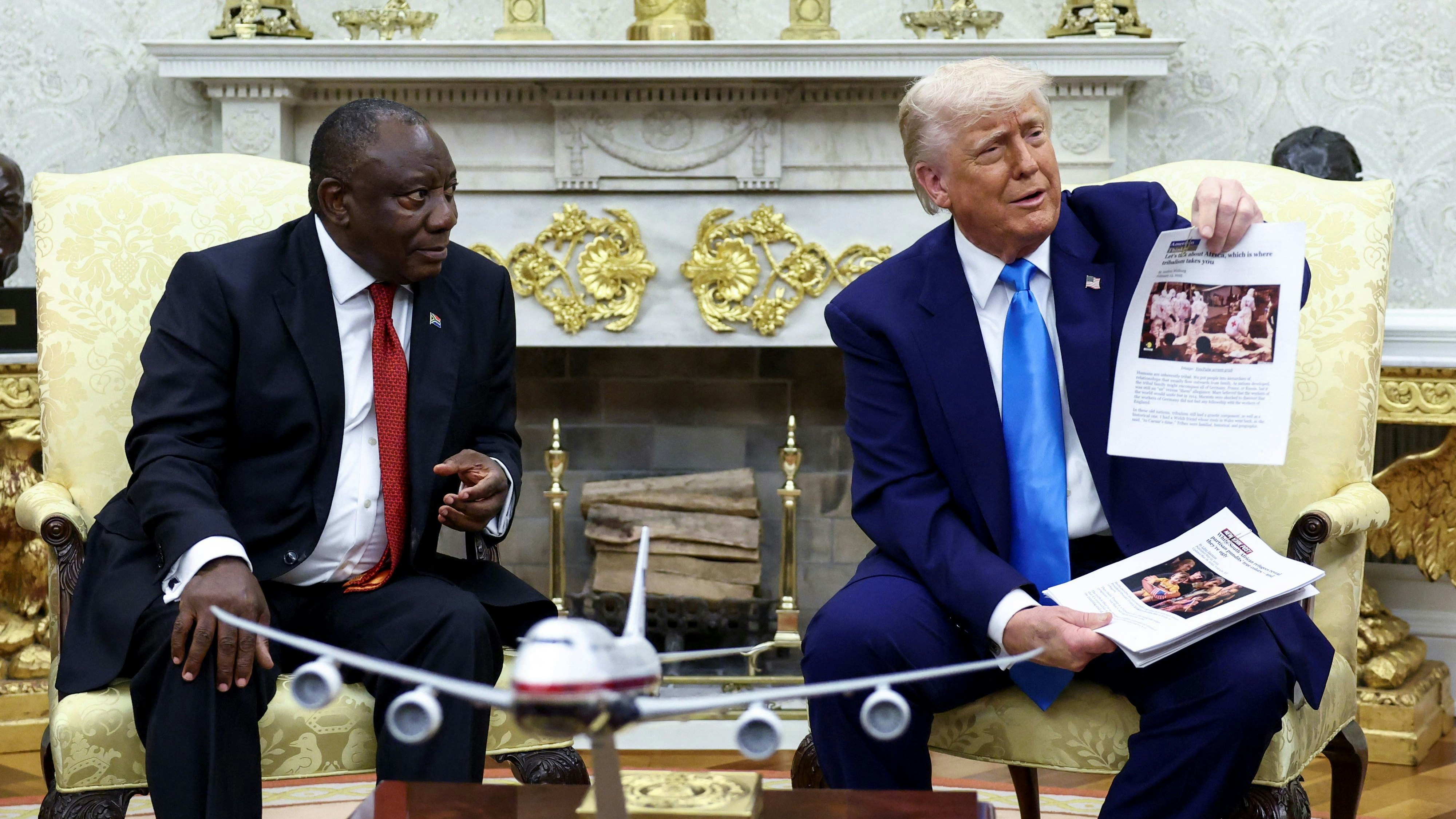 Donald Trump hält neben Cyril Ramaphosa ein Foto in die Kameras, das einen "Genozid an weißen Bauern" in Südafrika beweisen soll, aber aus einem ganz anderen Land stammt. (21. Mai 2025)