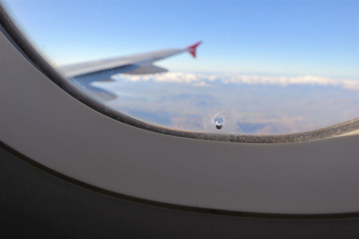 Klein, aber wichtig: das Loch im Flugzeugfenster spielt eine wichtige Rolle, wenn es um den Druckausgleich geht.