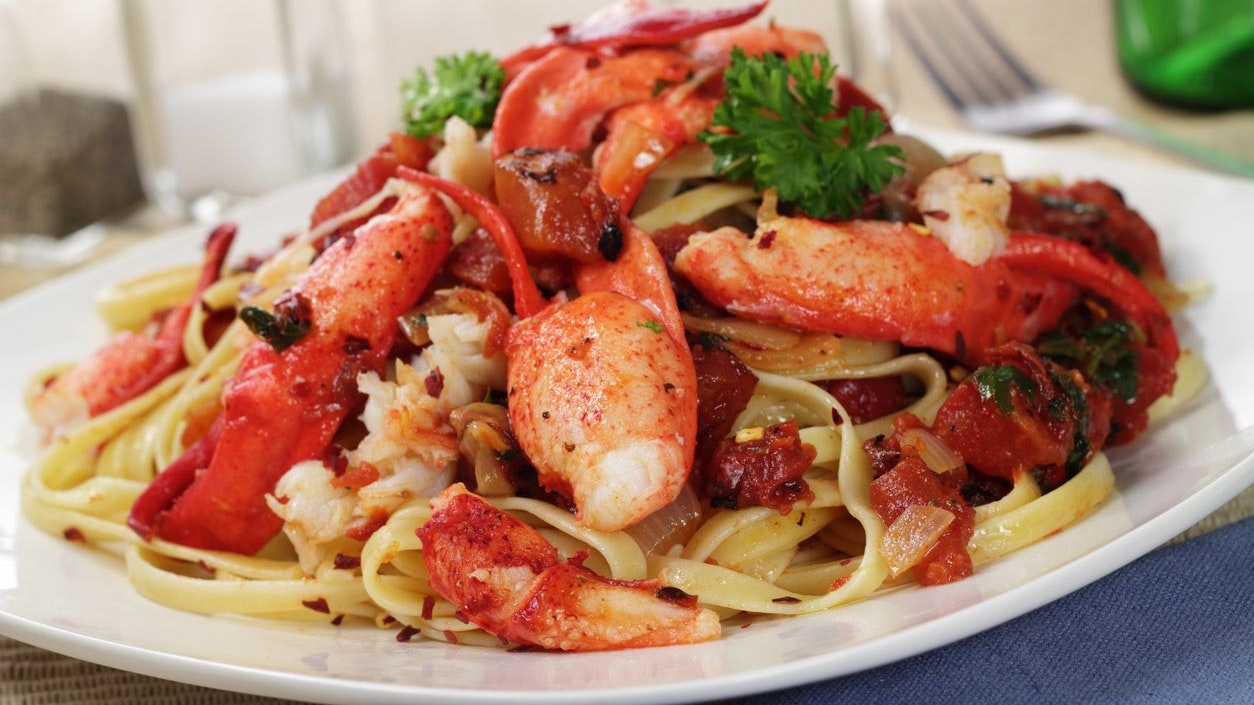 A plate of fettuccine pasta with Lobster and Fire roasted tomatoes in a spicy red pepper flake sauce