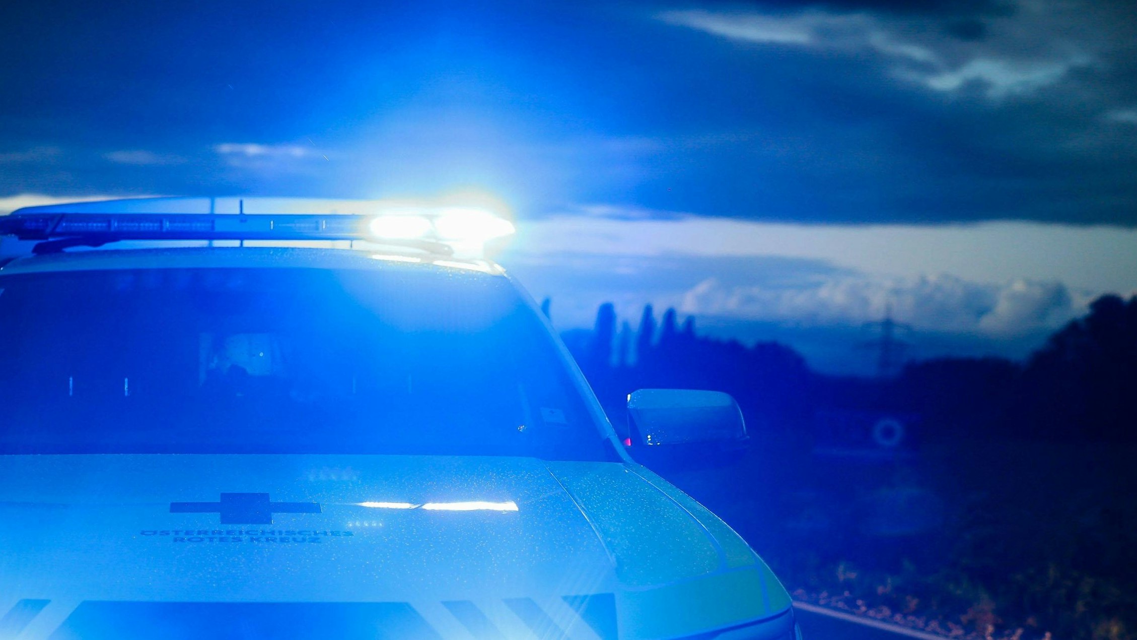 01.10.2024, Burgkirchen, AUT, Unterwegs in Oberösterreich, Symbolbild, Themenbild, Verschiedene Themenbilder, Unfall, Einsatzkräfte, Polizei, Rettung, Notarzt, Feuerwehr, im Bild Einsatzwagen, Notarzt, Erste Hilfe, Notarztwagen, Das Bild zeigt ein Notarzt-Einsatzfahrzeug des Rettungsdienstes in Oberösterreich vom Stützpunkt Braunau. Das Fahrzeug ist ein weißer Volkswagen mit auffälligen rot-gelben Markierungen und einem beleuchteten Blaulicht. Es ist auf einer Landstraße bei Regen zu sehen, Landstraße, Regen, Abenddämmerung, Unfallstelle, Rettung, Erste Hilfe, *** 01 10 2024, Burgkirchen, AUT, On the road in Upper Austria, symbol picture, theme picture, various theme pictures, accident, emergency services, police, rescue, emergenc
