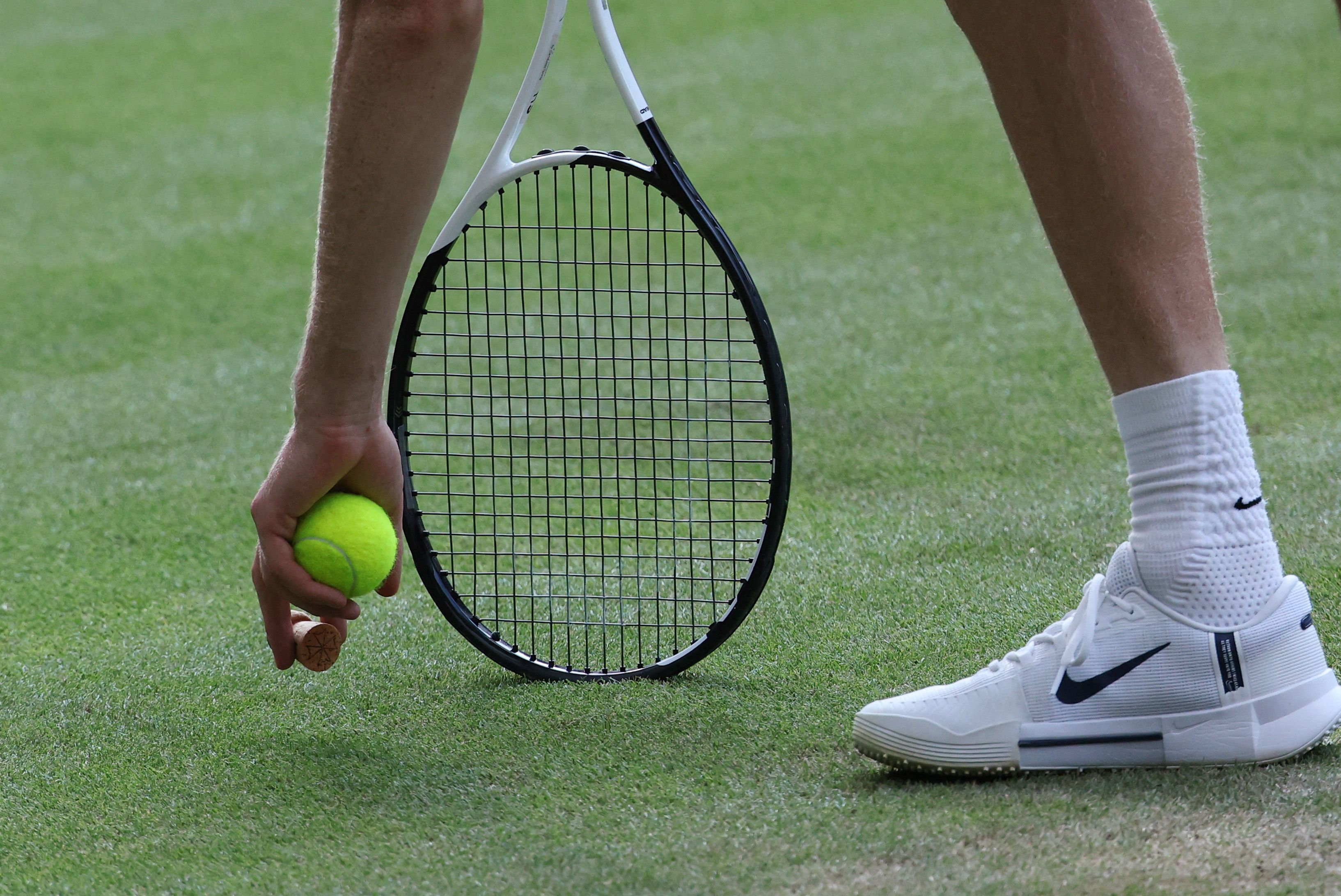 Sinner entfernt den Champagner-Korken vom Rasen.