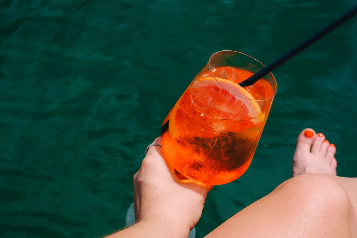 Aperol Spritz hat eine leuchtend orange Farbe und einen bittersüß-fruchtigen Geschmack. Der Likör wird mit Prosecco und Sodawasser zum Cocktail gemischt.