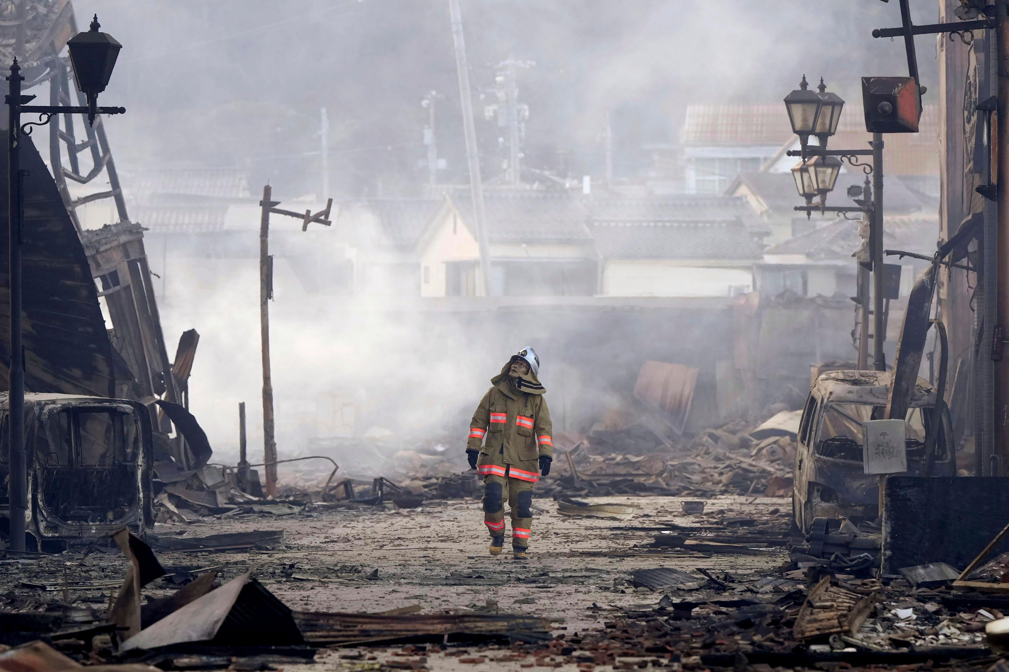 Ein Feuerwehrmann auf dem Weg durch ein völlig zerstörtes Wohnviertel der Stadt Wajima nach einem schweren Beben.