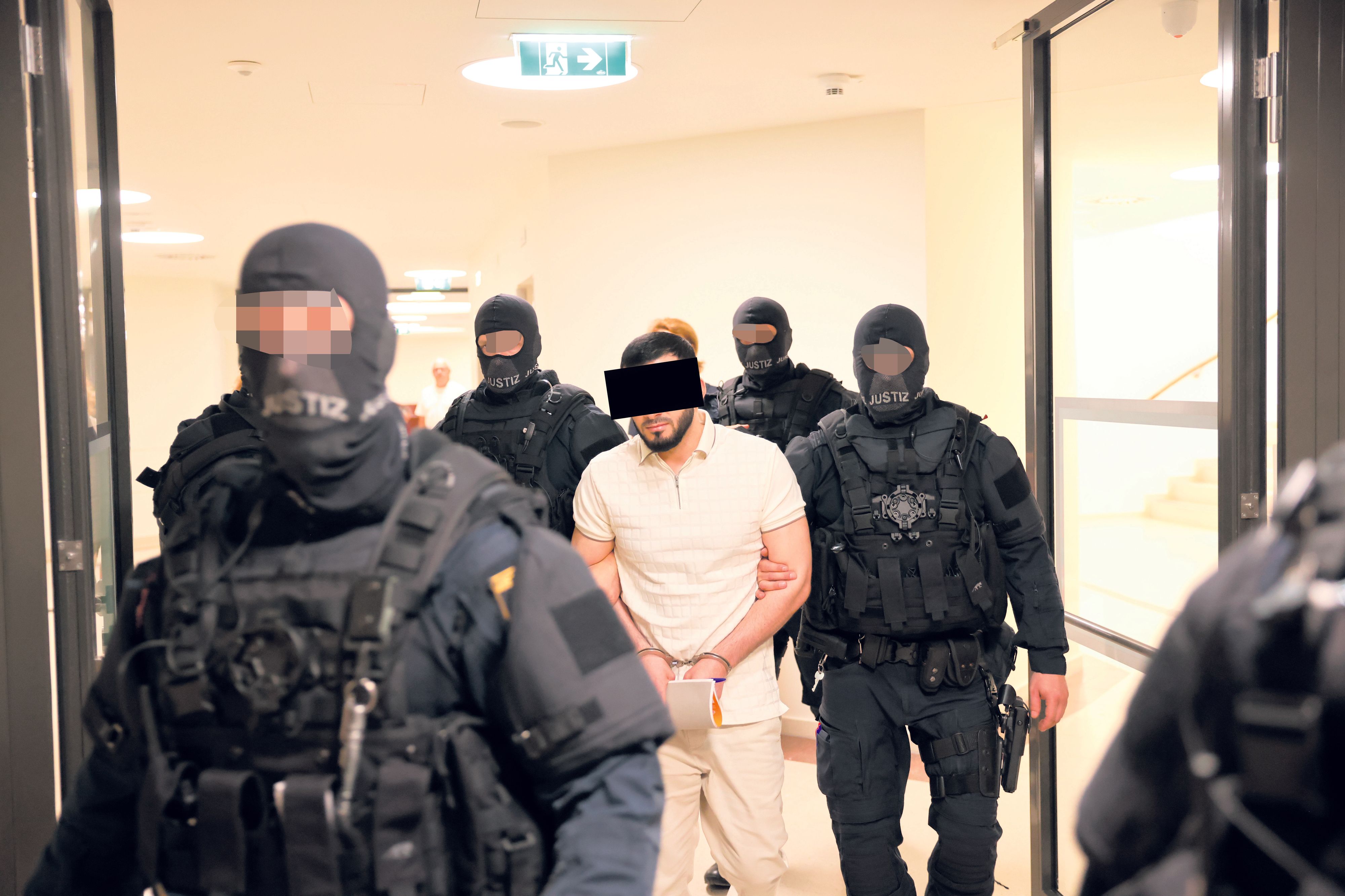 Der angeklagte 33-Jährige mit schwerbewaffneten Beamten. 