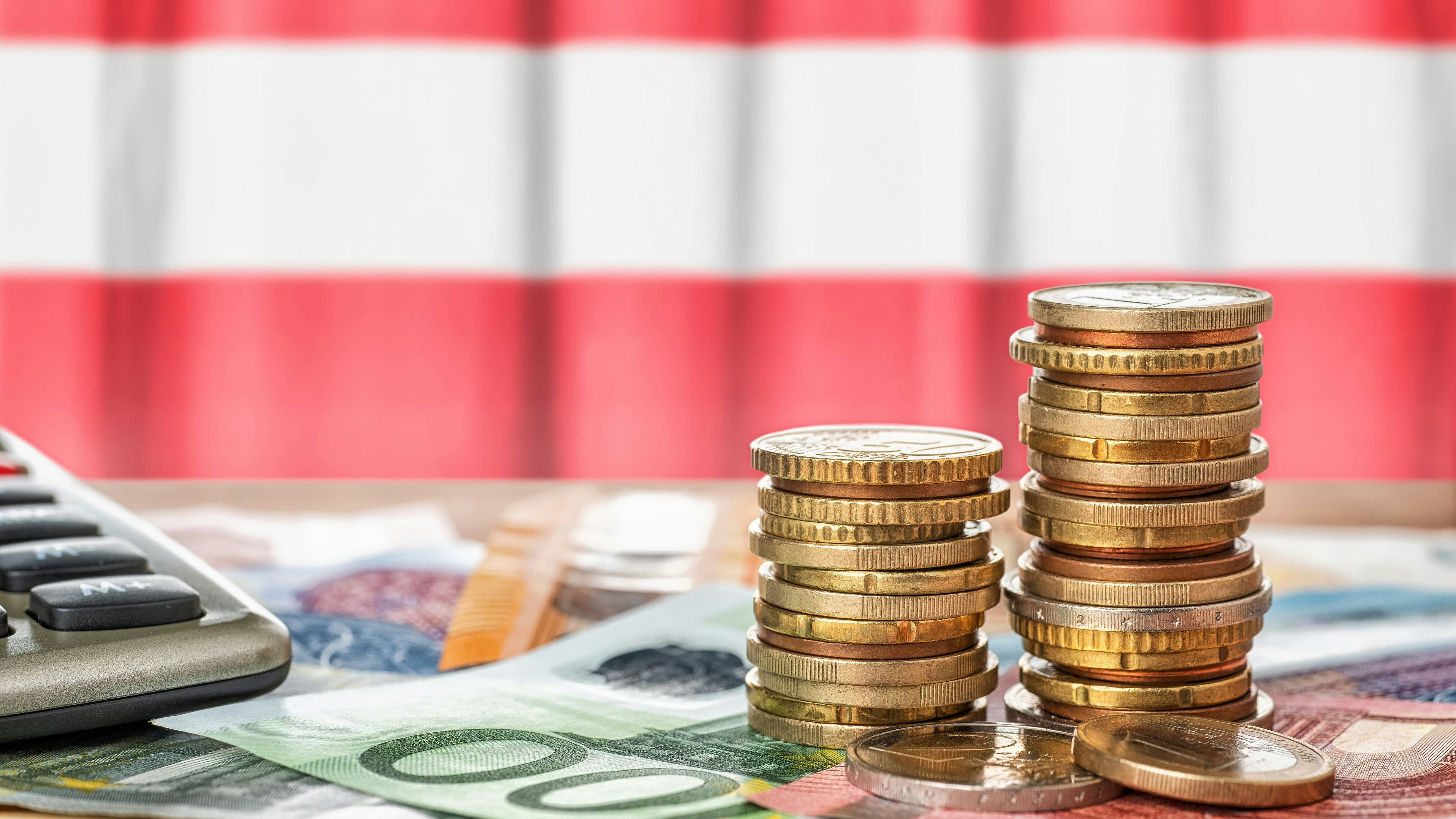 Euro banknotes and coins in front of the national flag of Austria