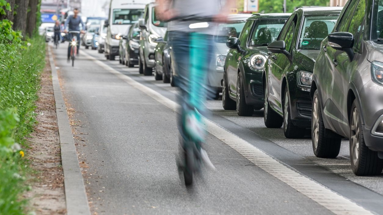 an e-scooter on the bike path overtakes cars in a traffic jam