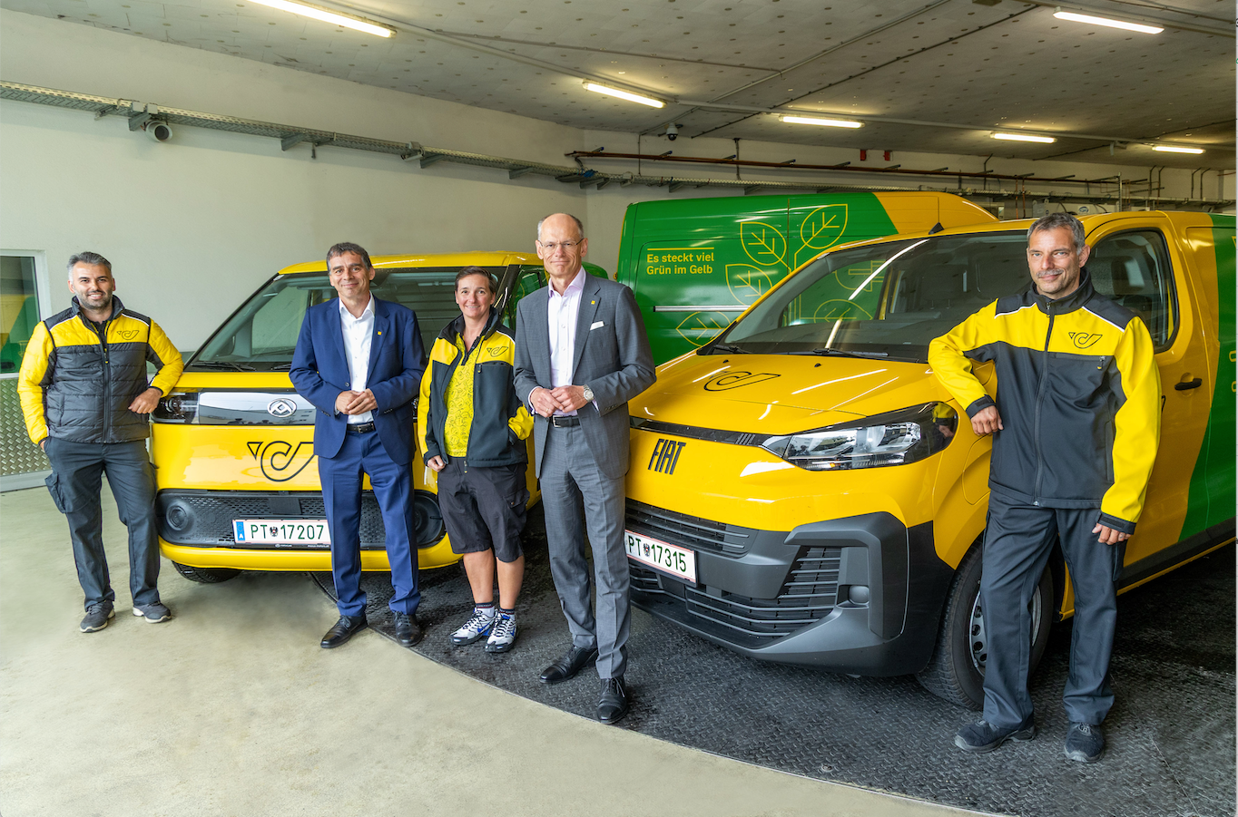 Peter Umundum (links), Vorstand für Paket & Logistik, Österreichische Post AG, und Walter Oblin (rechts), Generaldirektor, Österreichische Post AG, mit drei Wiener Zusteller*innen, die zukünftig alle mit E-Fahrzeugen unterwegs sein werden