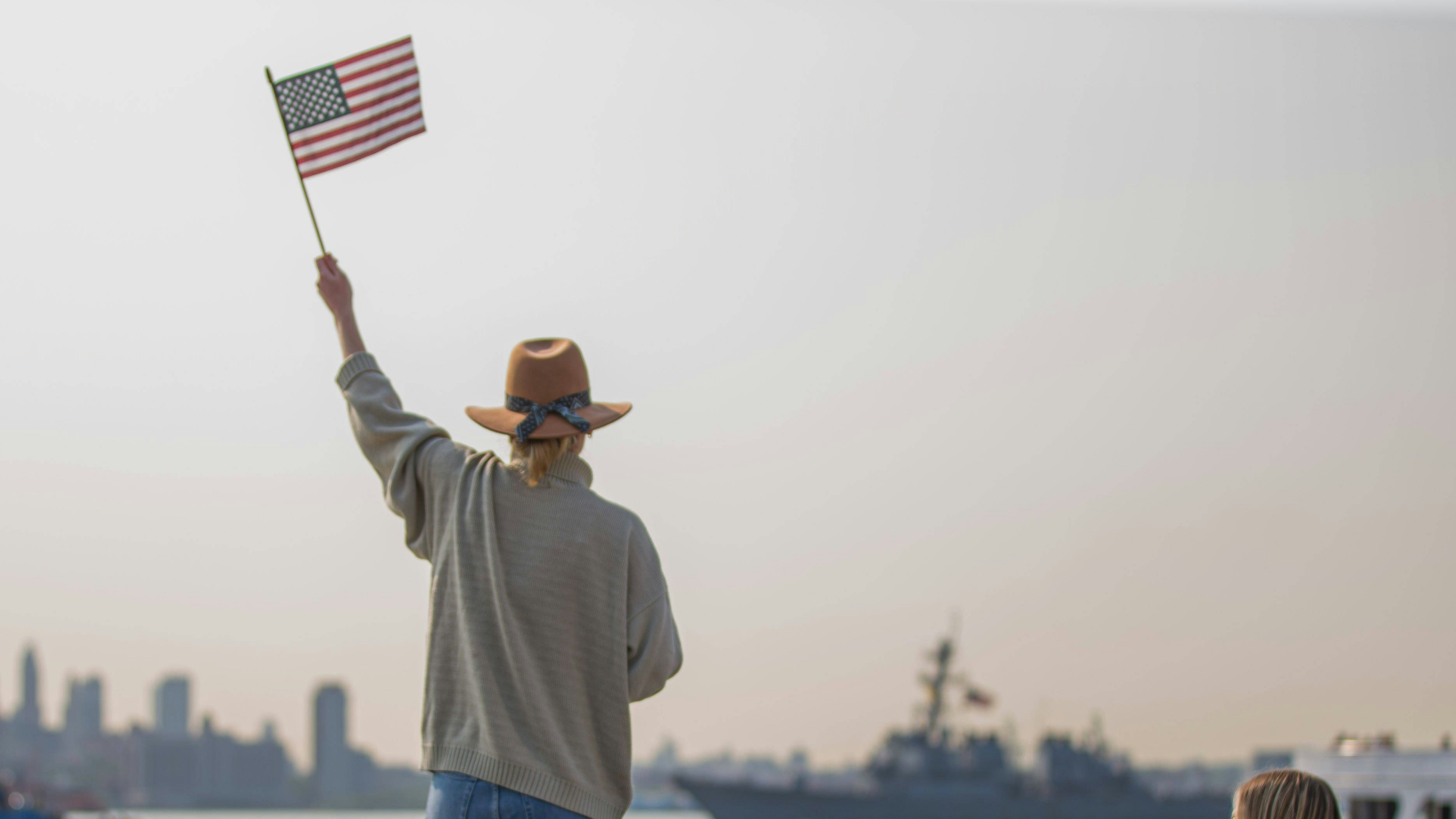 News Bilder des Tages May 24, 2023, New York, New York, USA: A woman waves an American Flag as US Navy vessels are arriving in New York for Fleet Week a US Navy tradition, seen from Liberty State Park it is possible to observe the arrival of the vessels with New York City in the background. New York City USA - ZUMAv122 20230524_zap_v122_031 Copyright: xWilliamxVolcovx