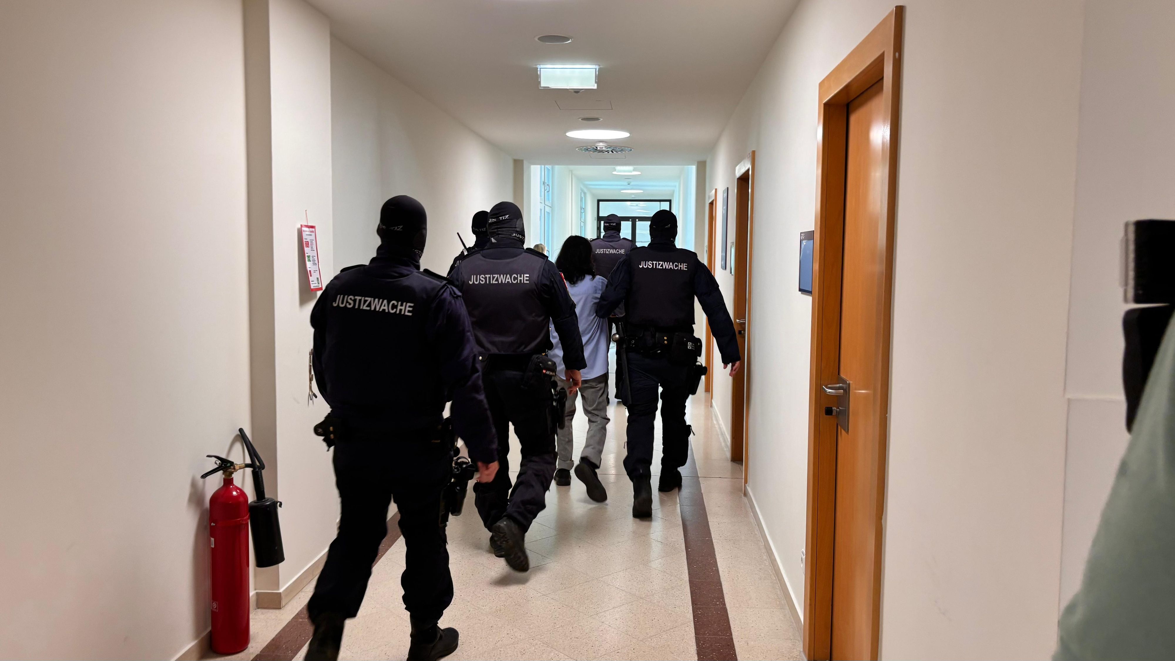 Der 15-jährige Angeklagte wird nach der Urteilsverkündung von mehreren Justizwachebeamten abgeführt.