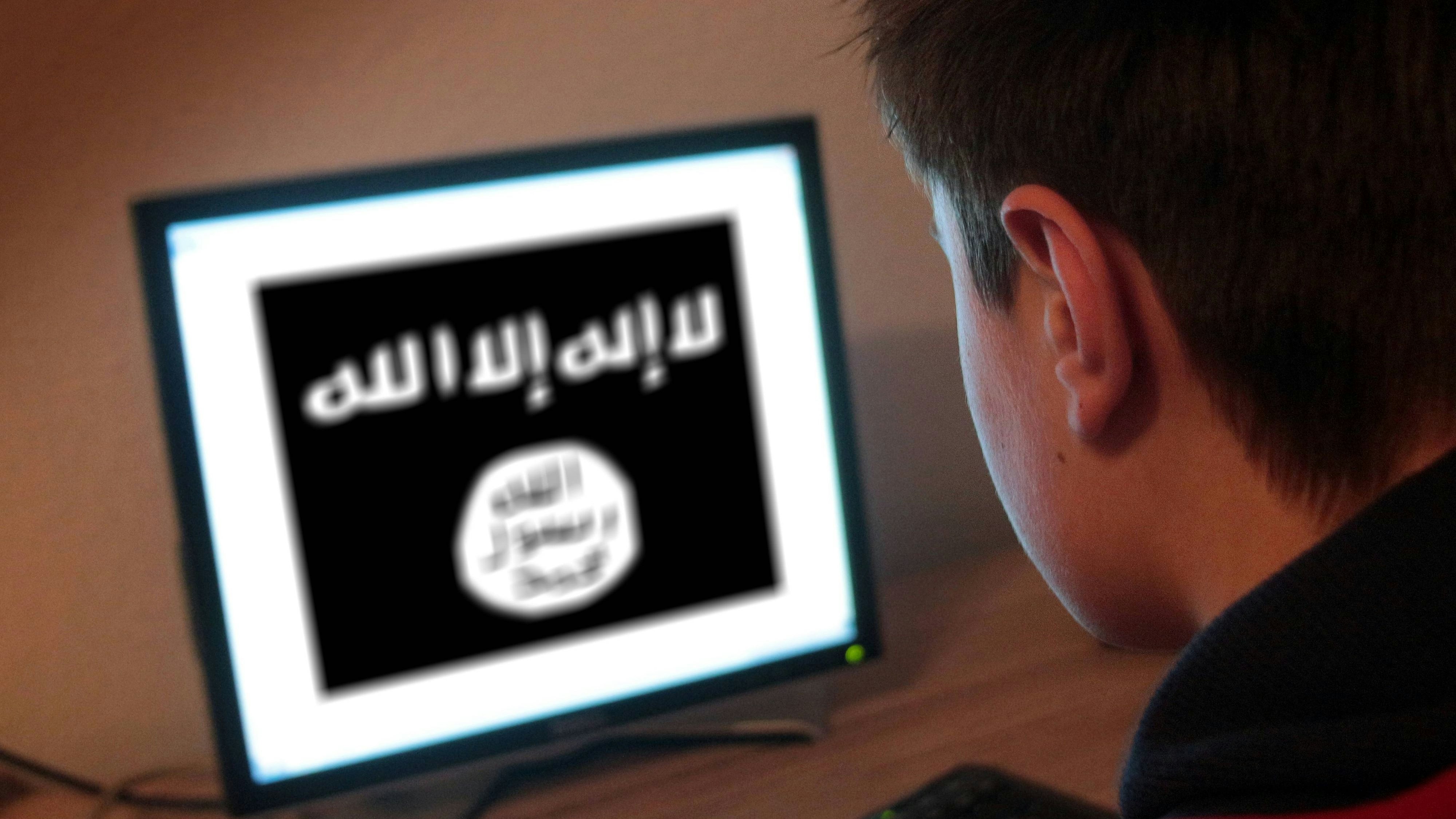 Symbolbild zu den Anwerbeversuchen der radikal-islamistischen IS Islamischer Staat bei minderjährigen Jugendlichen: Jugendlicher sitzt am Bildschirm eines PC s mit Flagge des IS Islamischer Staat  Symbol image to the  the radical Islamist IS Islamic State at Minors Young people Young people sits at Screen a PC S with Flag the IS Islamic State