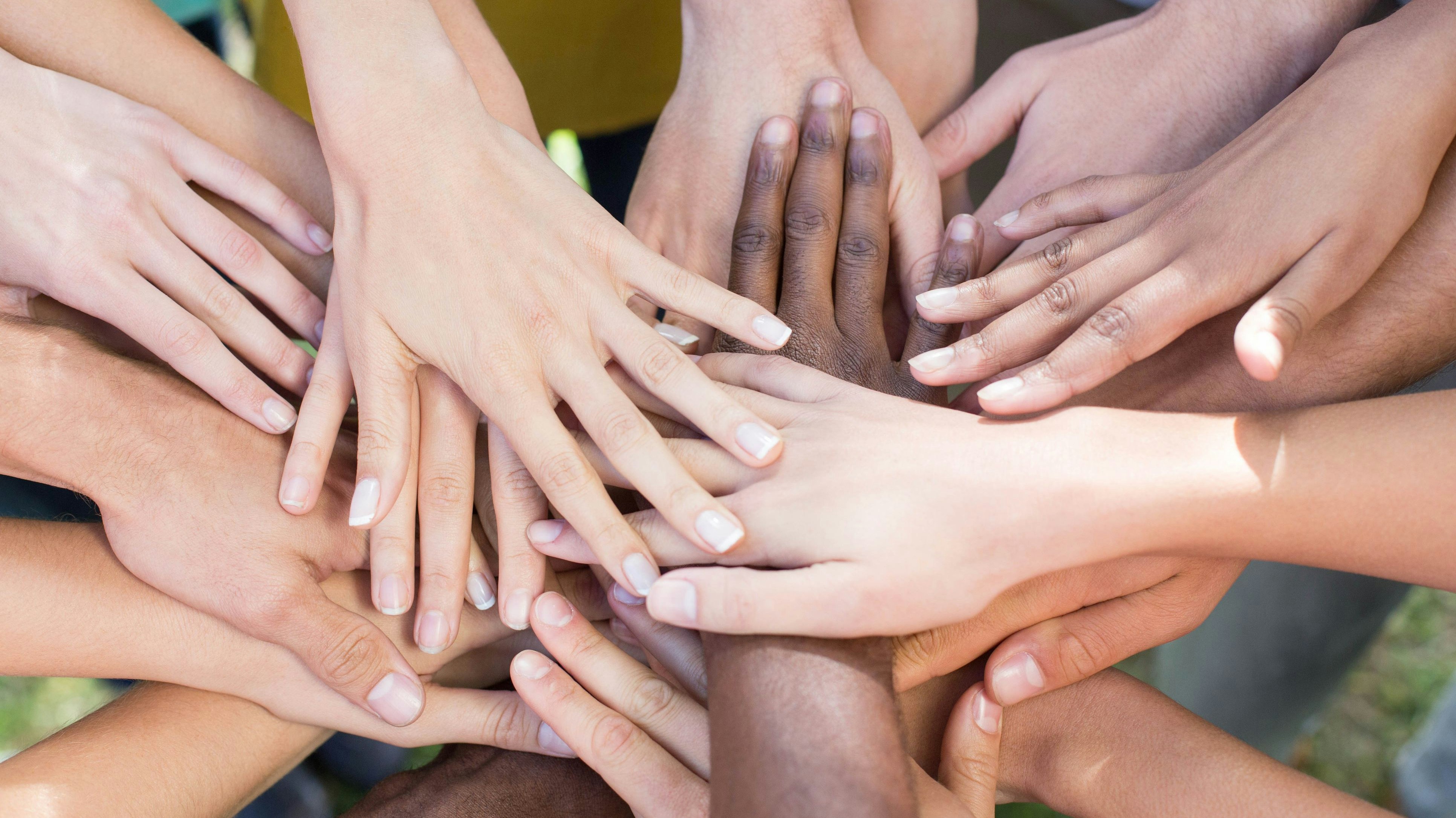 Friends putting their hands together on a sunny day