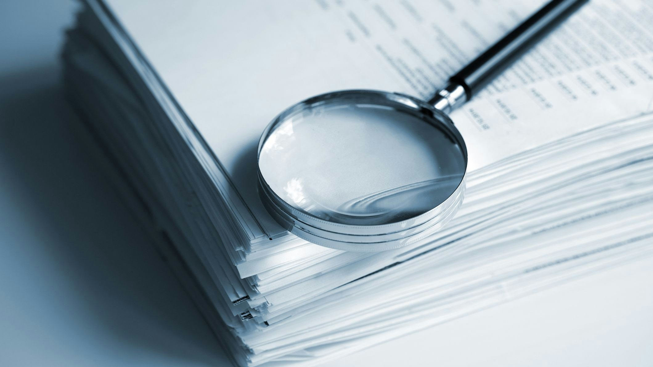Magnifying glass on a stack of documents