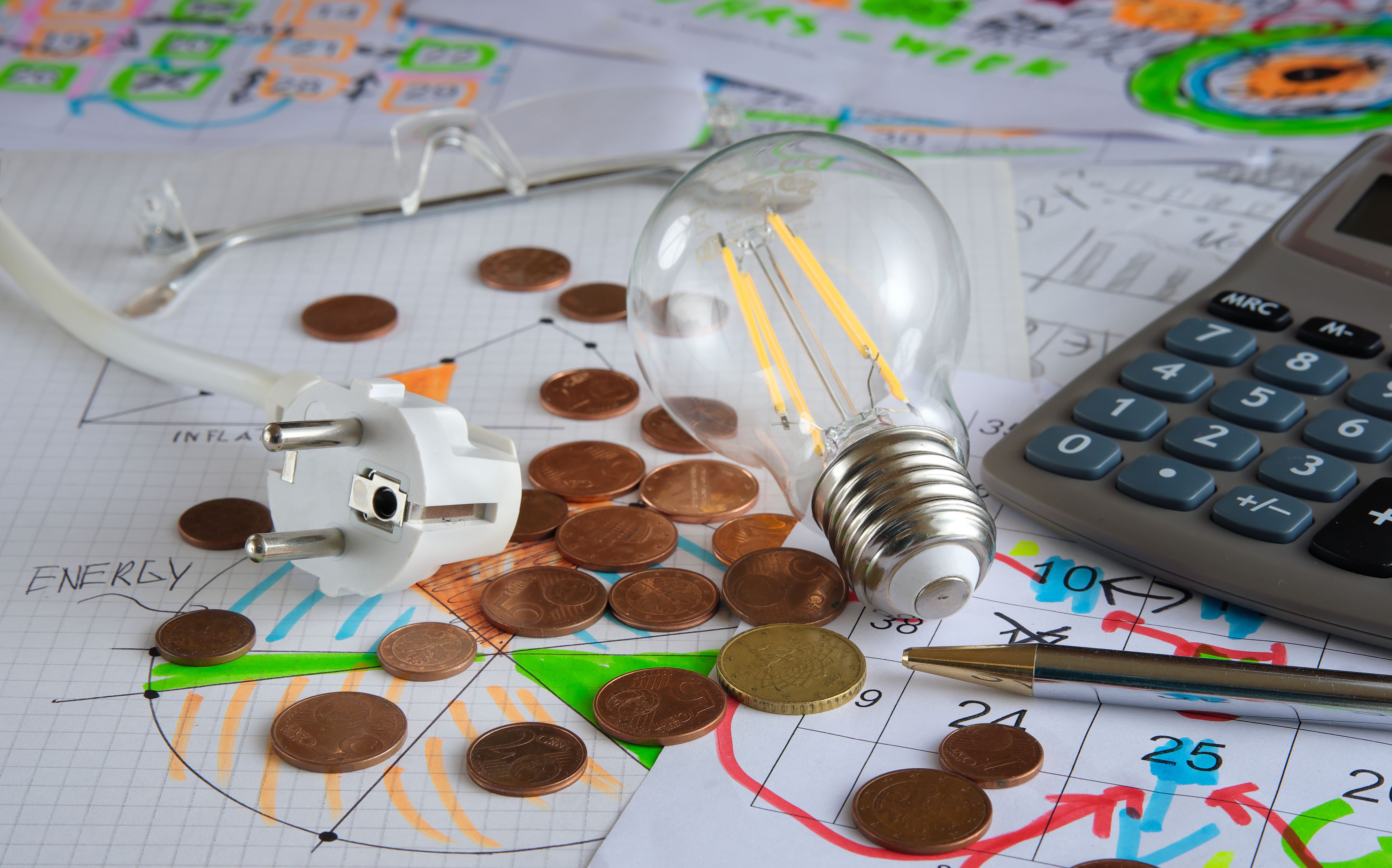 Business concept: Planning for energy costs in the monthly budget. Still life with calculator,light bulb, plug and diagrams