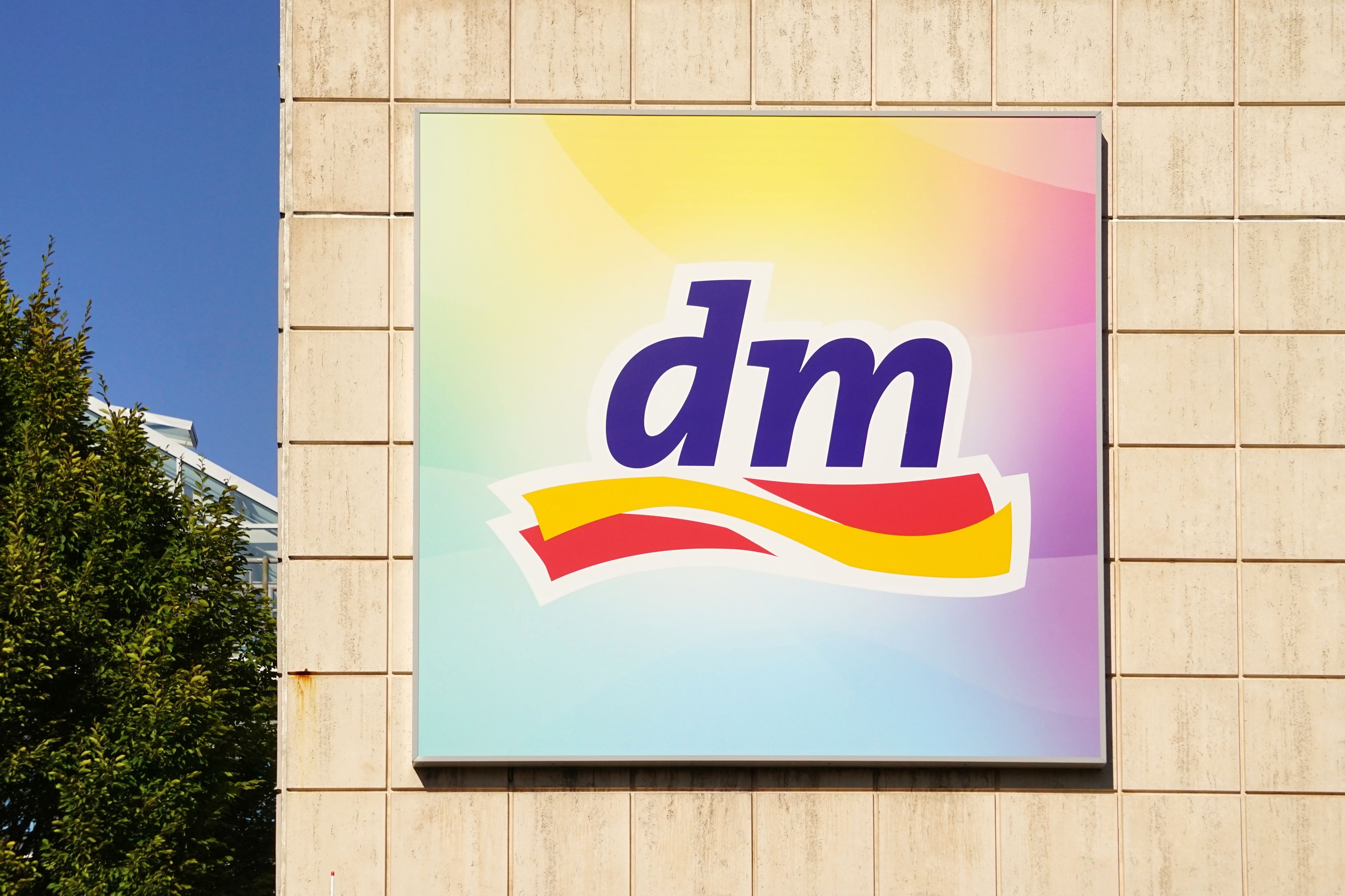 Das Firmenlogo von dm an einem Gebäude.