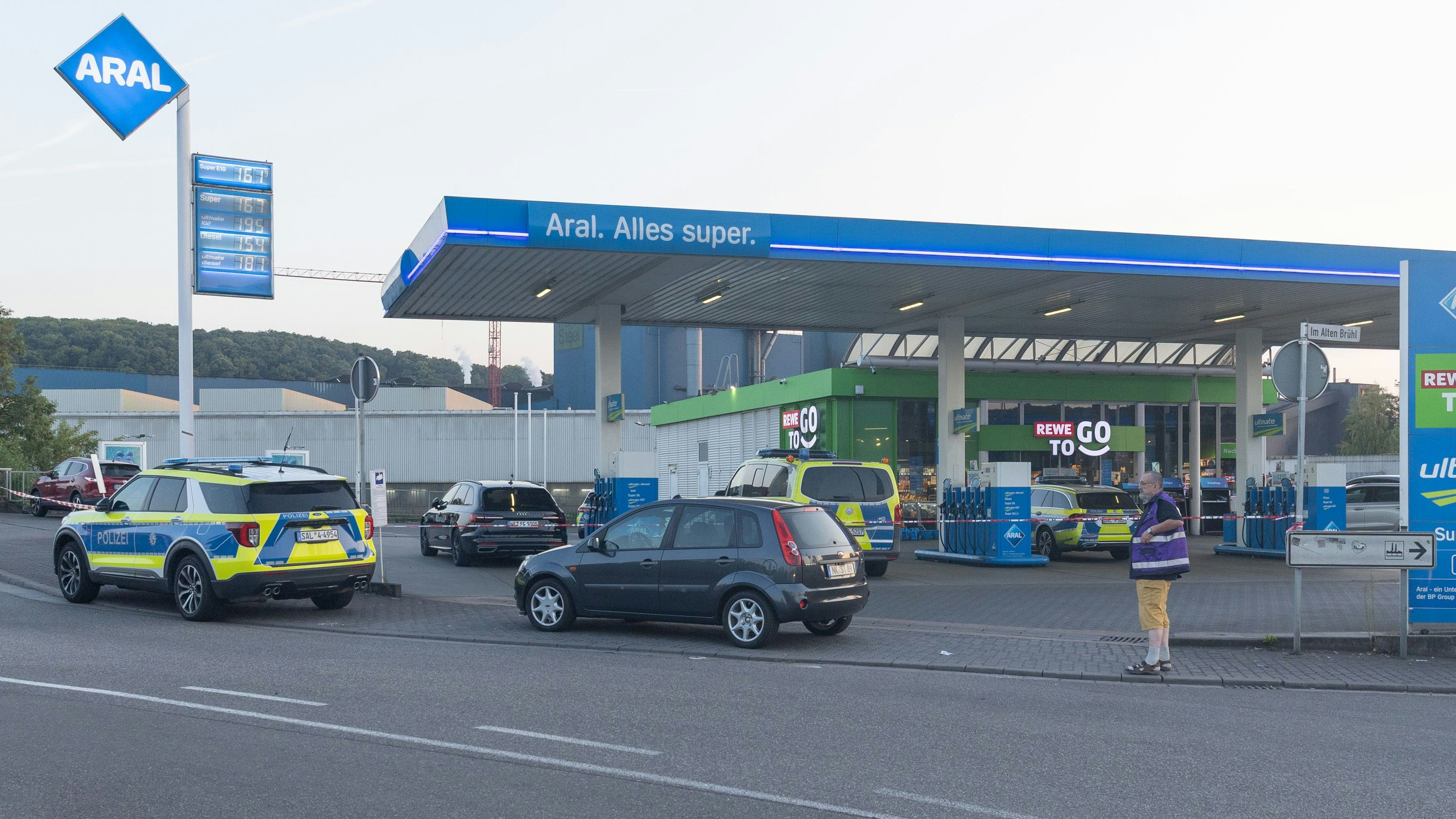 Download von www.picturedesk.com am 22.08.2025 (08:06).  ACT action_48165931 -- .Tödlicher Schusswechsel nach Tankstellenüberfall in Völklingen.Völklingen, 21. August 2025 - Am heutigen Nachmittag kam es in Völklingen zu einem schweren Raubdelikt mit anschließendem Schusswechsel zwischen einem Tatverdächtigen und Einsatzkräften der Polizei Am Späten Donnerstag nachmittag ging bei der Polizei die Mitteilung über einen Überfall auf eine Aral-Tankstelle an der Karolinger Brücke ein. Sofort wurden mehrere Streifenwagen zum Einsatzort entsandt Auf dem Weg zum Tatort trafen die Einsatzkräfte auf den flüchtenden Tatverdächtigen. Während der Überprüfung der Person und im Zuge der Festnahme kam es zu einem Gerangel zwischen dem Mann und den eingesetzten Polizeibeamten. Dabei gelang es dem Tatverdächtigen, einem der Beamten die Dienstwaffe zu entreißen Unvermittelt gab der Tatverdächtige einen Schuss auf einen der Polizisten ab. Daraufhin kam es zu einem gegenseitigen Schusswechsel, bei dem sowohl der Tatverdächtige als auch ein Beamter verletzt wurden. Der Tatverdächtige konnte anschließend überwältigt und festgenommen werden Der getroffene Polizeibeamte verstarb noch im Krankenwagen.Die öffentliche Sicherheit in Völklingen ist wiederhergestellt, so der Pressesprecher der Polizei. Es befinden sich keine bewaffneten Personen mehr auf der Flucht. Der Tatort wird derzeit mit starken Polizeikräften gesichert und umfassend kriminaltechnisch untersucht.- Völklingen, am Donnerstag (21.08.2025).Foto:Thomas Wieck - 20250821_PD11447 - Rechteinfo: Rights Managed (RM)