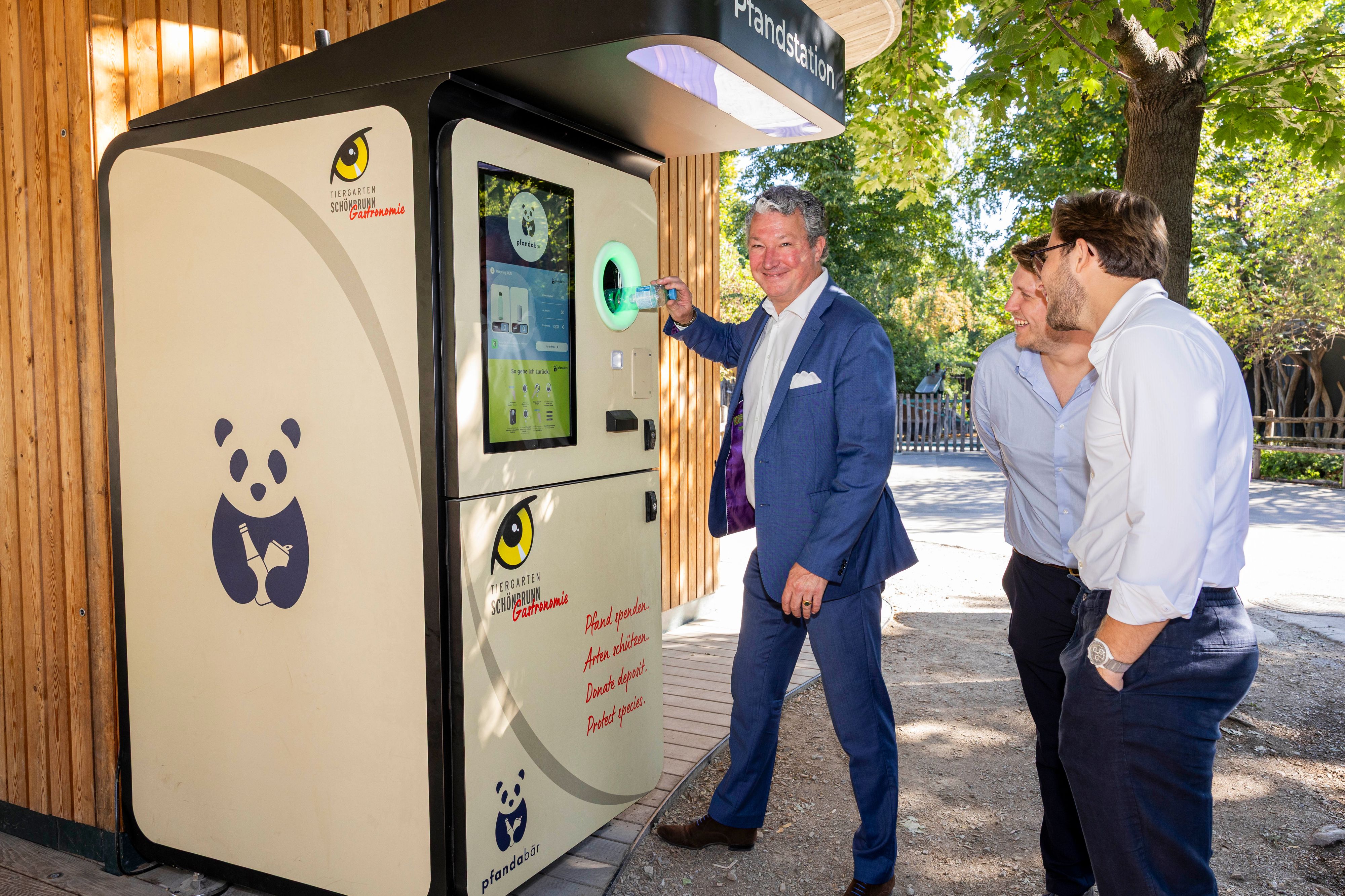Zoo-Direktor Stephan Hering-Hagenbeck testet den neuen 'Pfandabär'-Automaten im Tiergarten Schönbrunn, neben ihm die Gründer Raphael Thiele und Noah Matznetter.