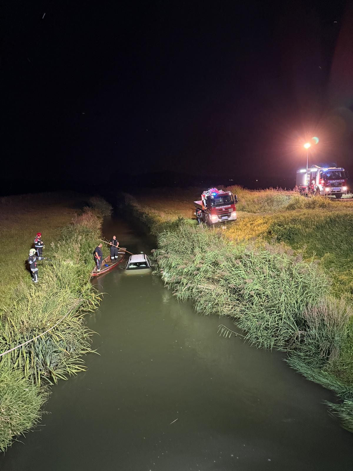 Das weiße Auto landete vom Feldweg im Bach.