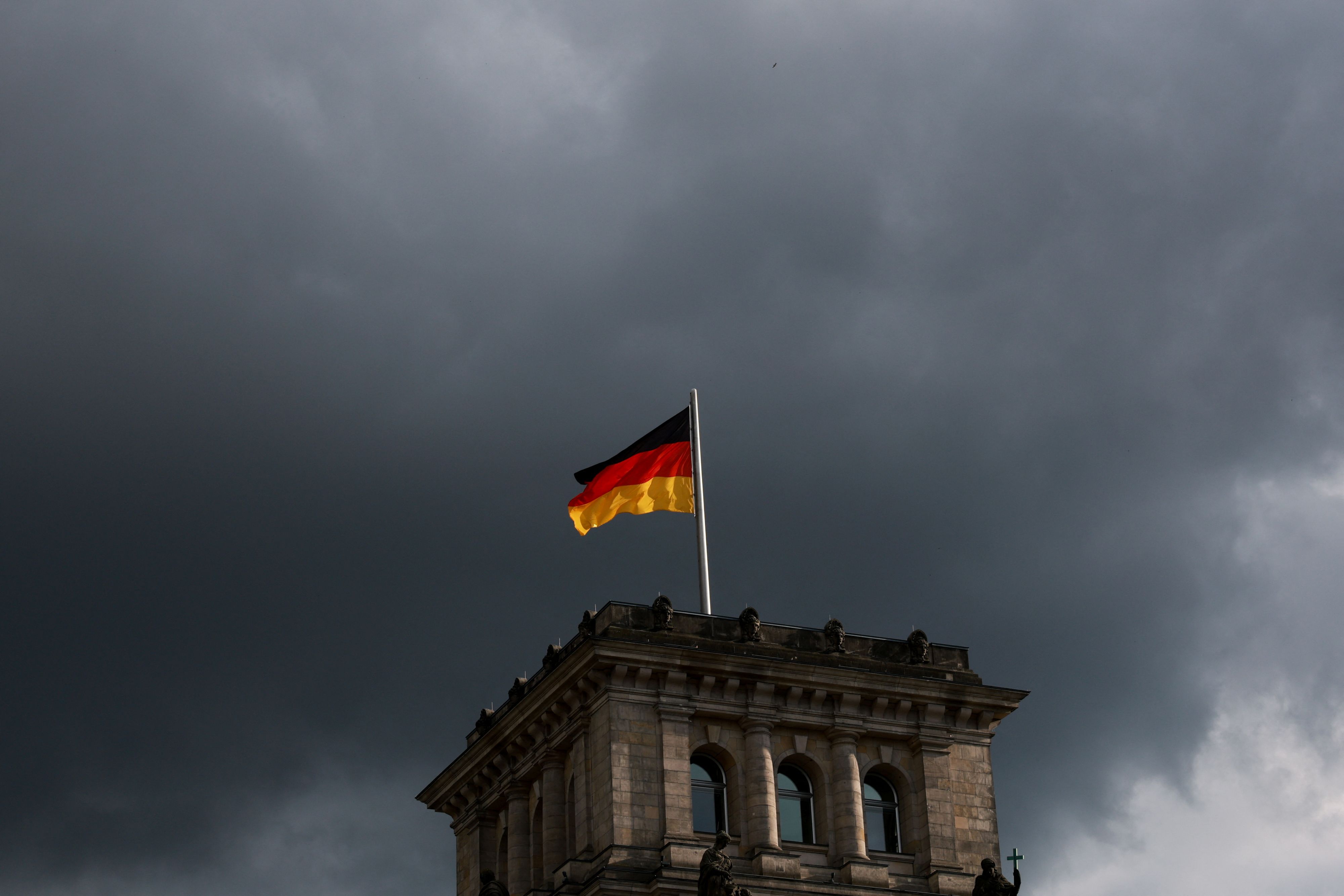 Dunkle Wolken über der deutschen Nationalhymne und Bundesflagge.