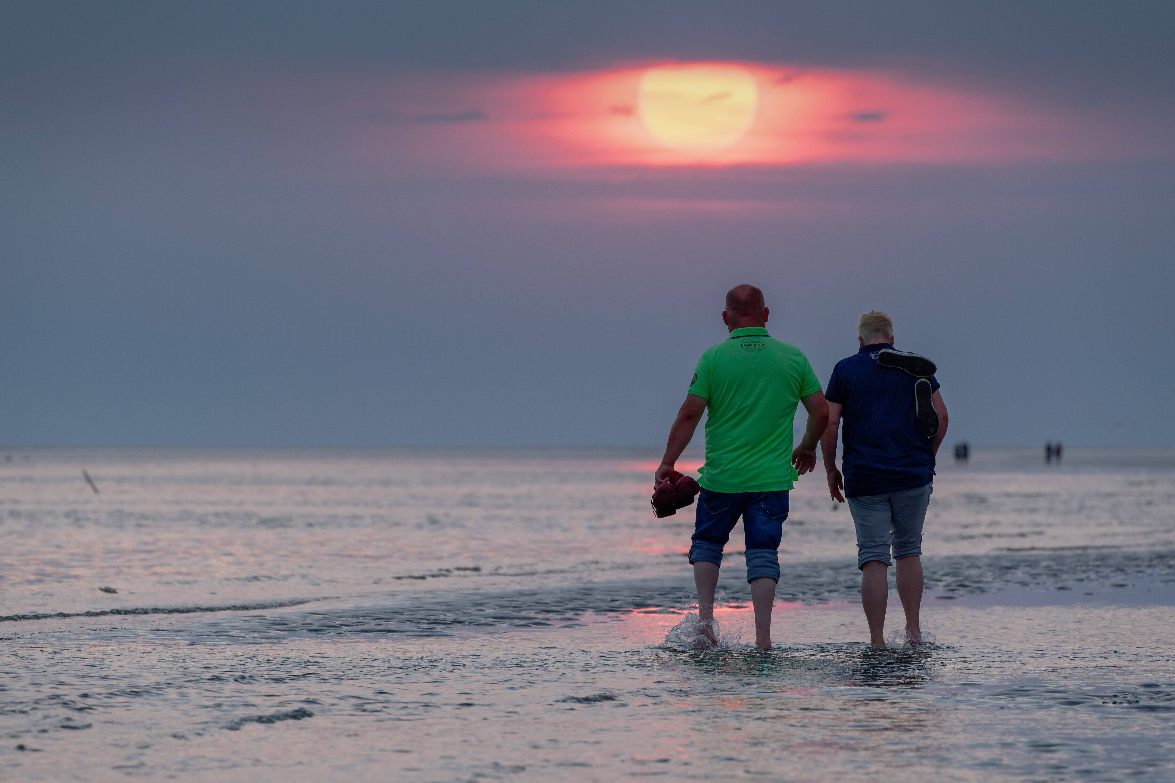 Zwei Besucher spaziert bei milden Temperaturen Mitte August über den Strand von Büsum, Schleswig-Holstein.