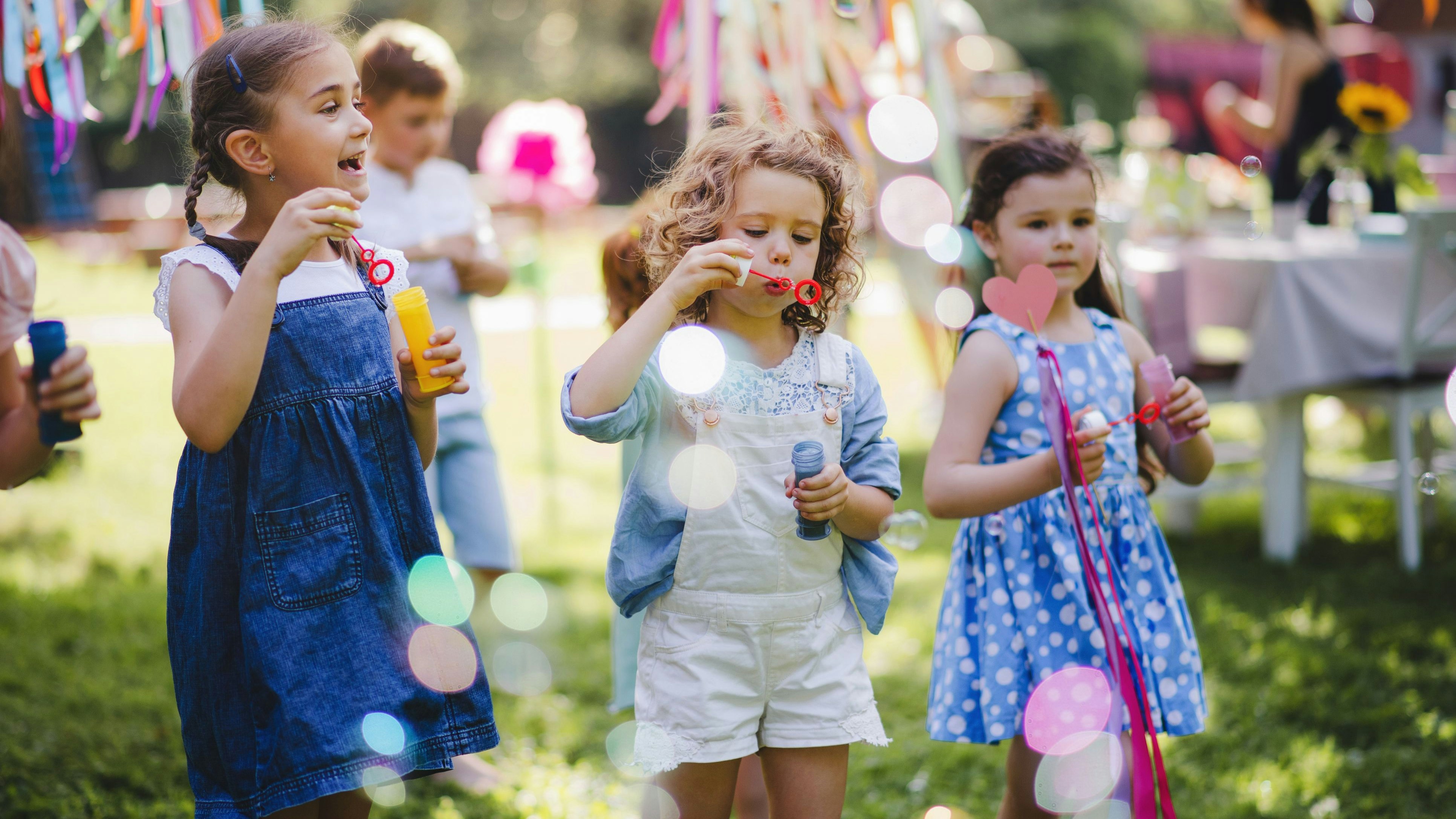 Small children outdoors in garden in summer, playing with bubbles. A celebration concept.