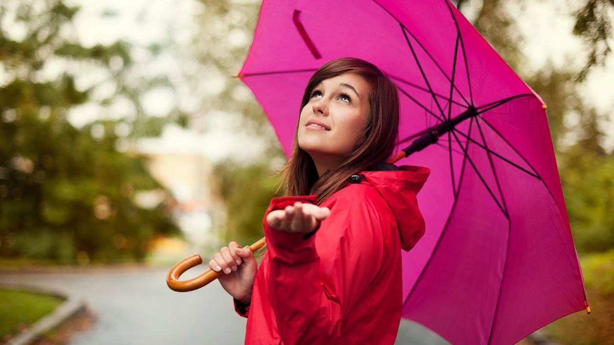 Beautiful woman with umbrella checking for rain