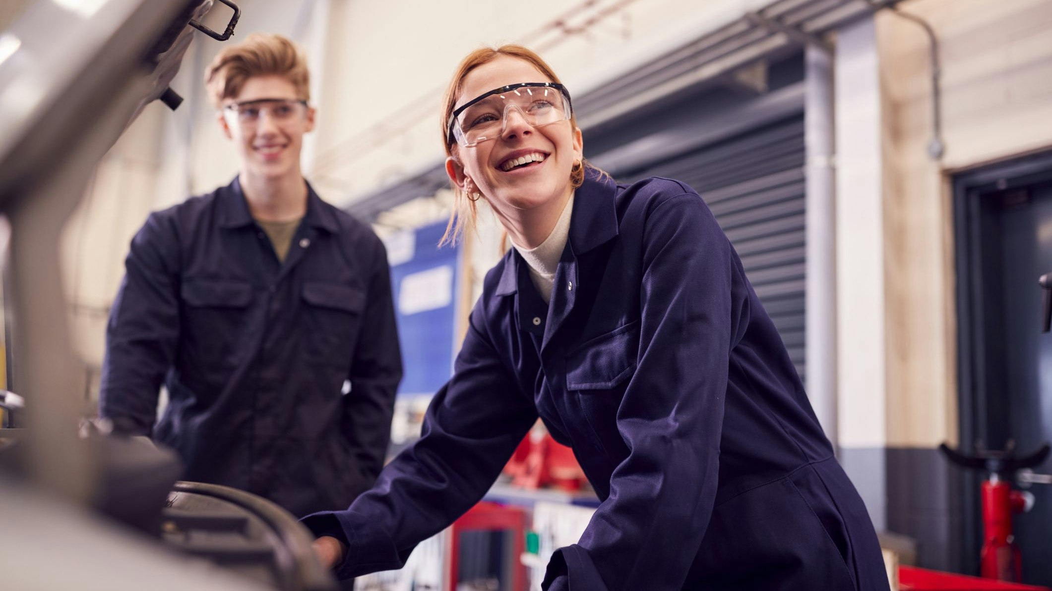Male And Female Students Looking At Car Engine On Auto Mechanic Apprenticeship Course At College