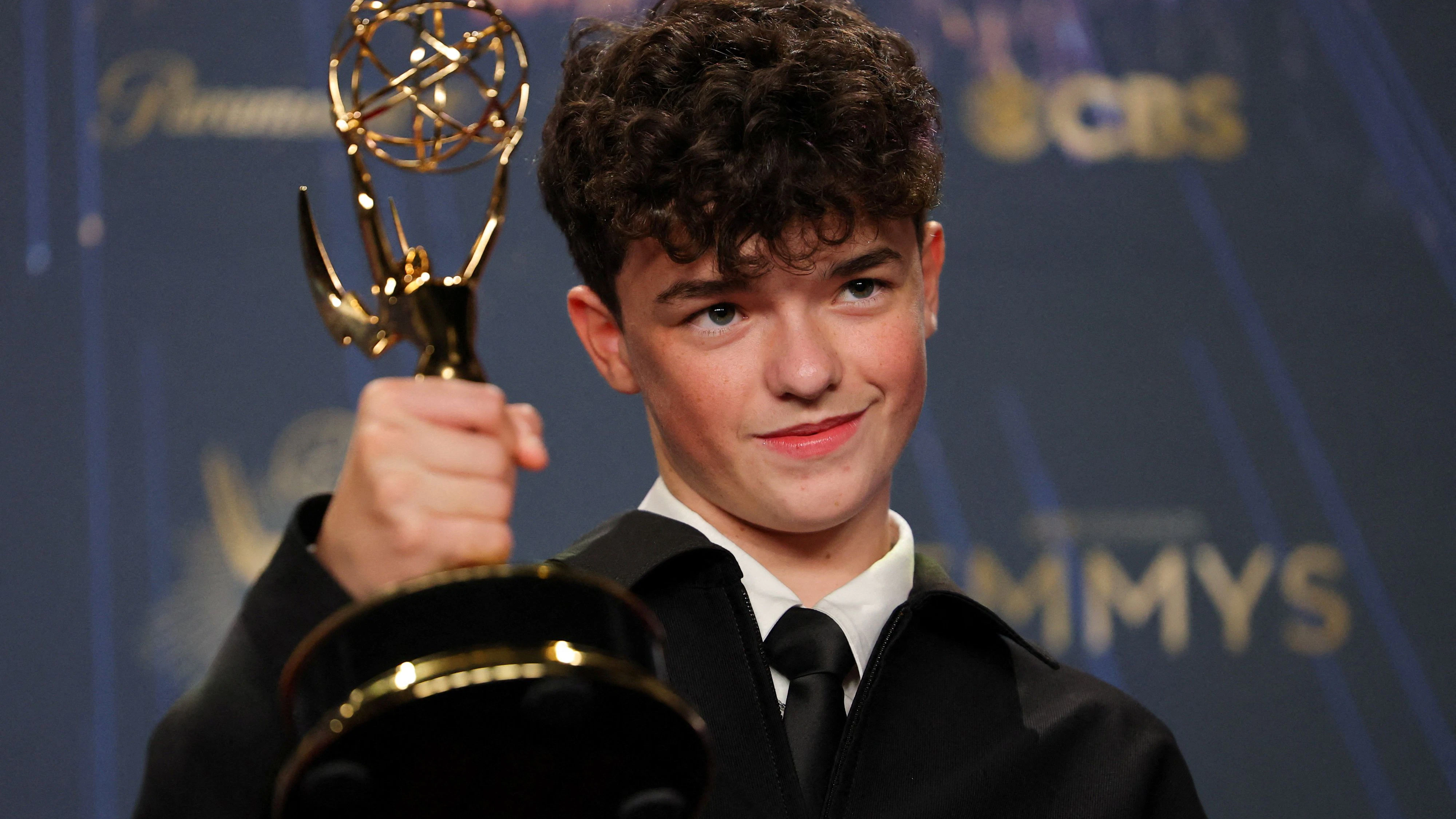 Owen Cooper posiert mit seinem ersten Emmy Award in einem klassichen schwarzen Anzug.