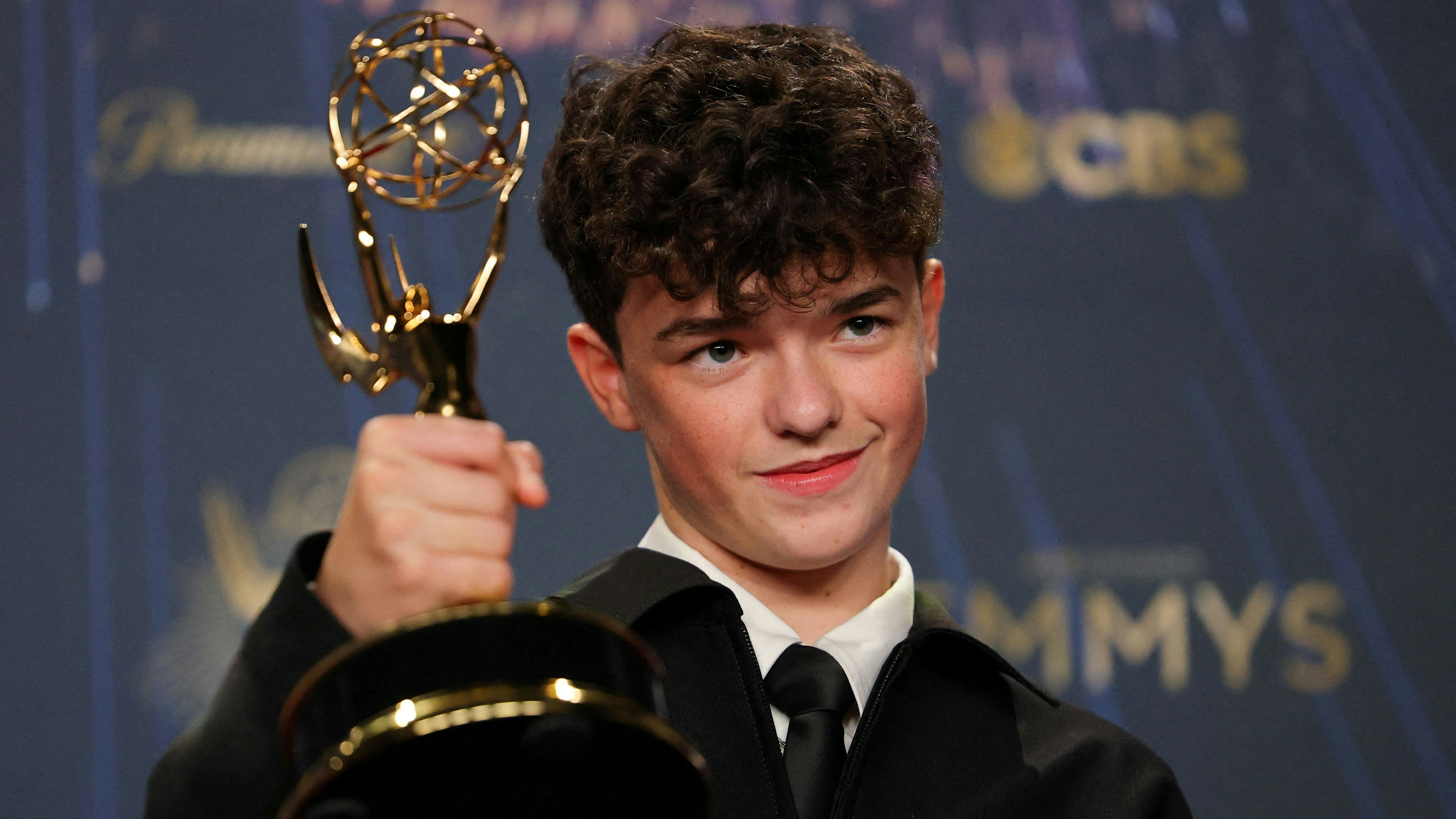 Owen Cooper posiert mit seinem ersten Emmy Award in einem klassichen schwarzen Anzug.