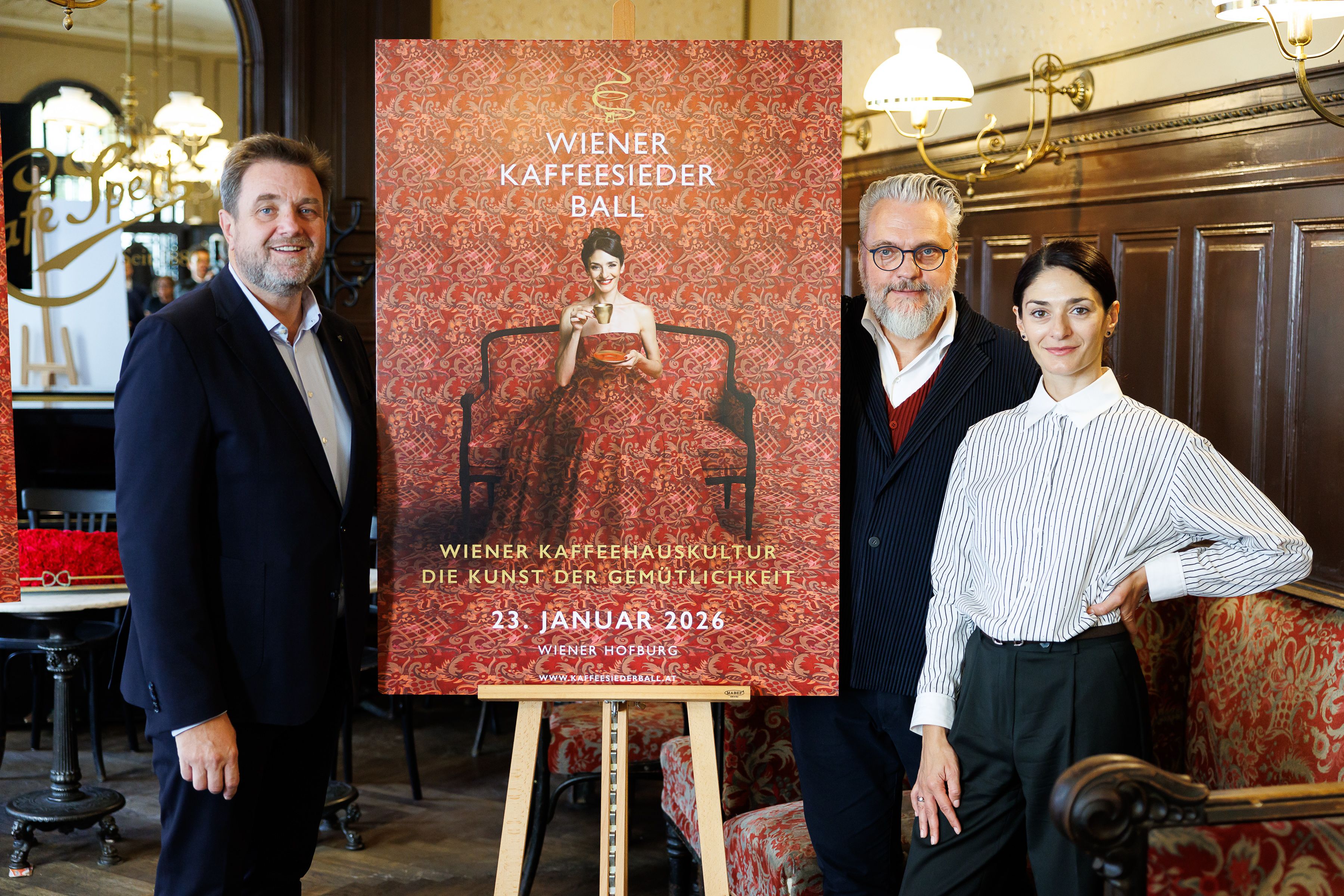 Balleiter Wolfgang Binder, Theater-Designer Christof Cremer und Balletttänzerin Ketevan Papava präsentierten das Ballplakat vom Kaffeesiederball 2026.