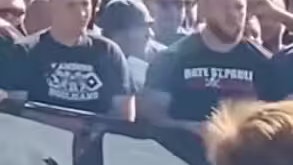 Auf einem der T-Shirts ist die HSV-Raute auszumachen. Direkt daneben ein Mann, auf dessen Shirt etwas mit St. Pauli steht. Ein weiterer Hinweis auf Hamburg. Zudem lässt es auf einen Fußballzusammenhang tippen.