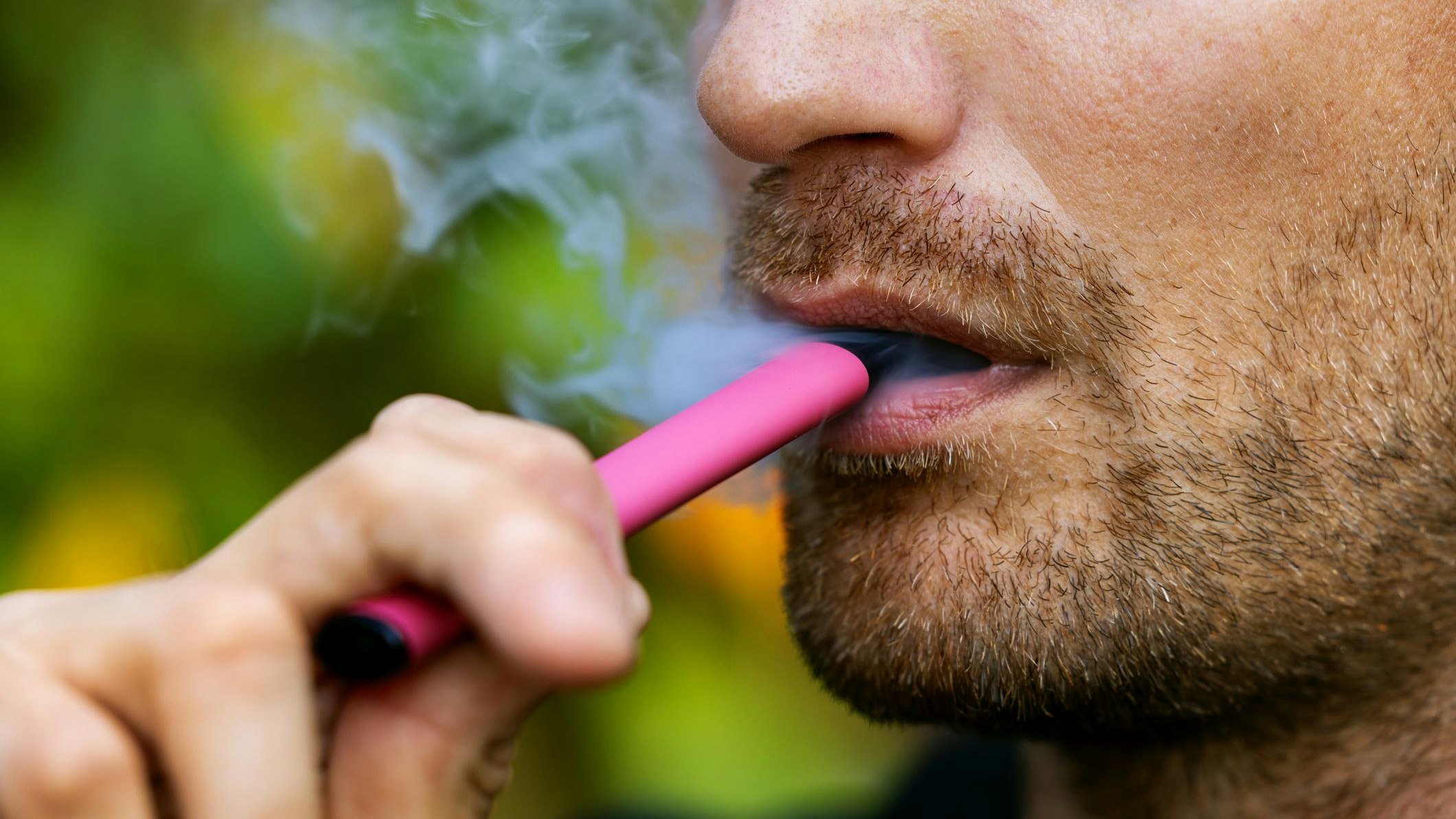 man smoking disposable electronic cigarette. face closeup