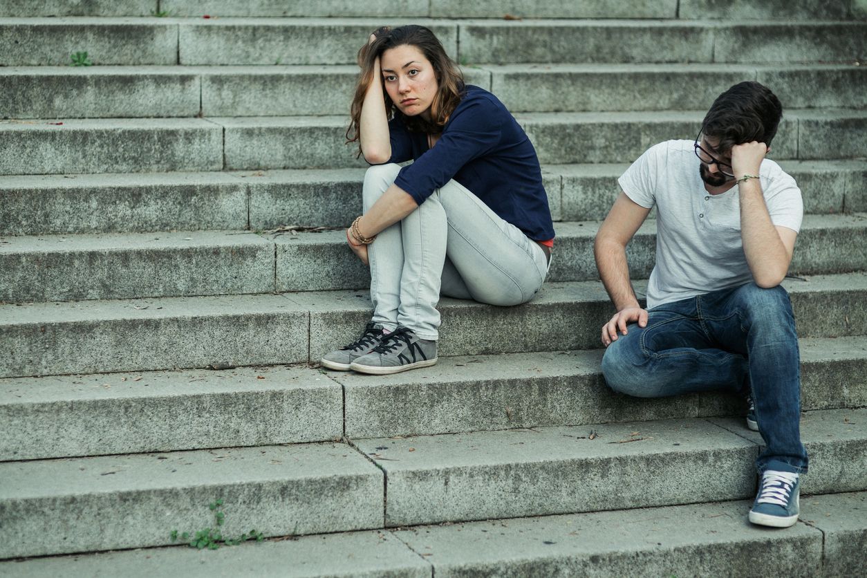 Couple ignoring each other while sitting on stairs back to back