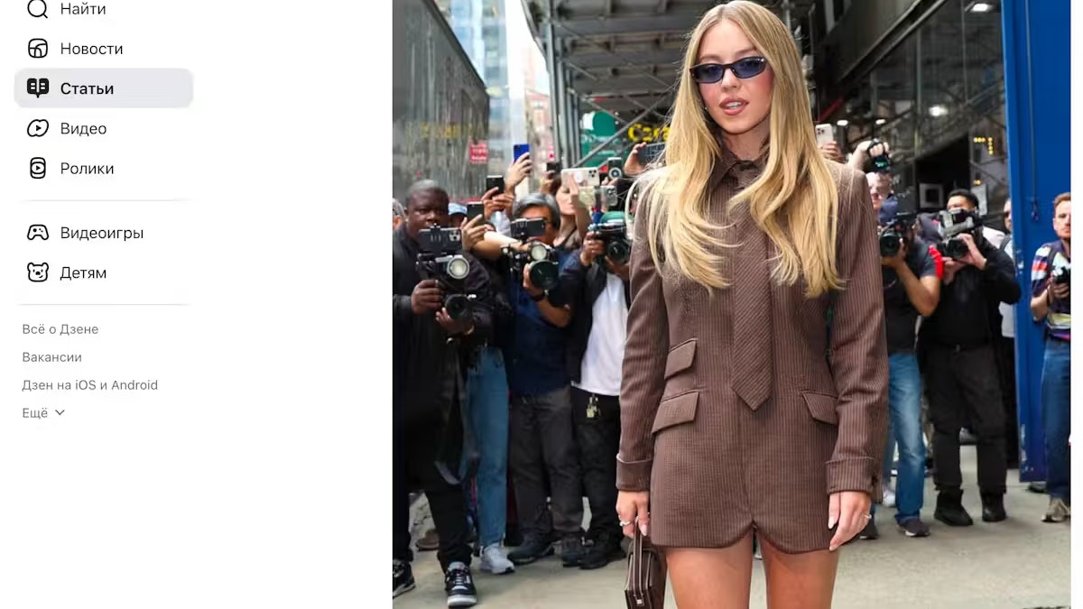 Er führt zu einem Blogbeitrag, auf dem ein Foto der Schauspielerin zu sehen ist, das sie in derselben Pose, aber in einem anderen Outfit zeigt.