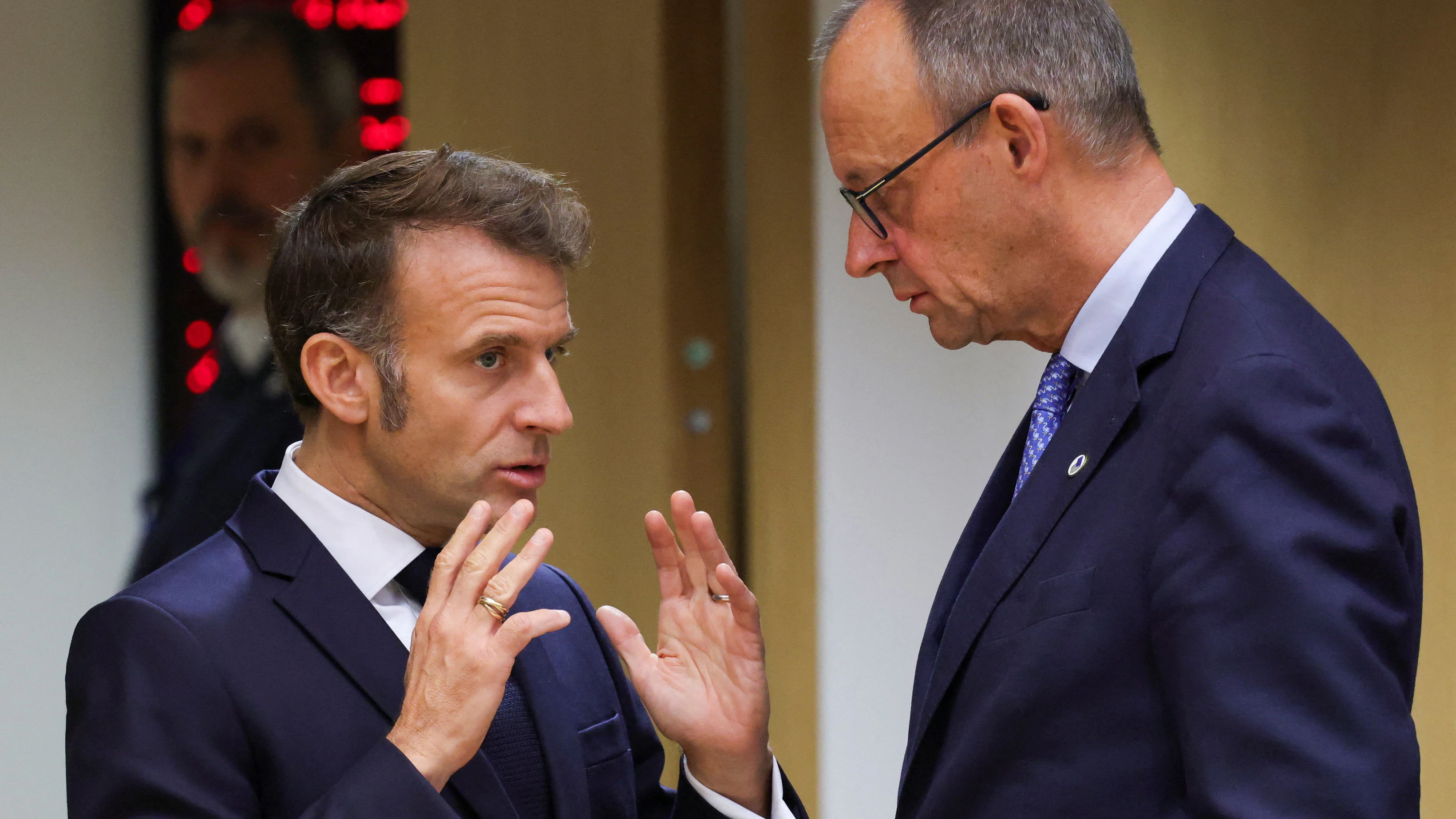 French President Emmanuel Macron and German Chancellor Friedrich Merz interact as they attend the European Union leaders' summit in Brussels, Belgium, October 23, 2025. REUTERS/Yves Herman   