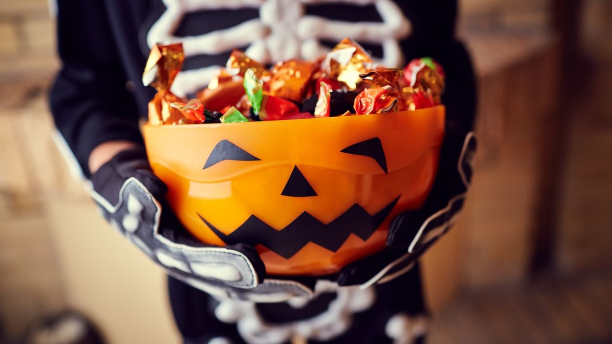 Boy in skeleton costume holding bowl full of candies