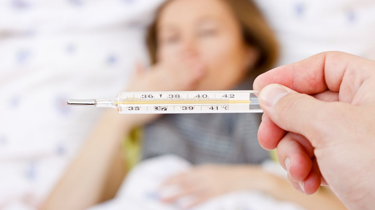 Young sick woman laying on bed having high fever