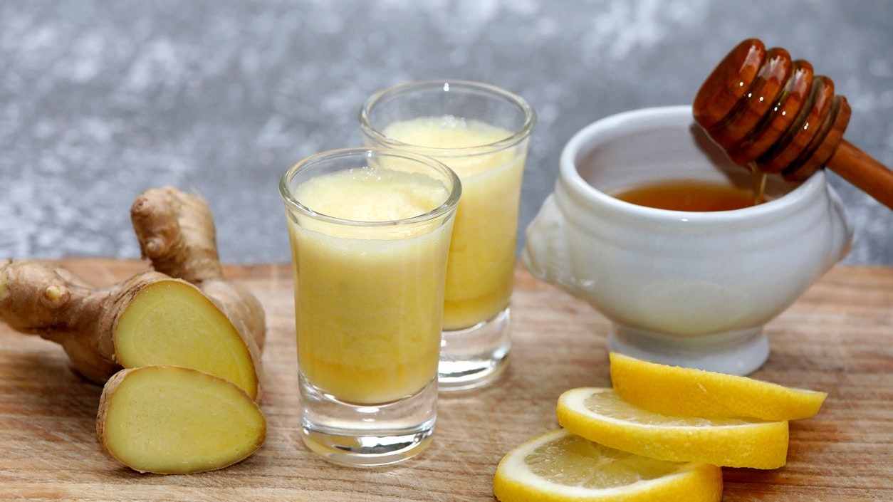 Drink with ginger root, honey and lemon on wooden background.