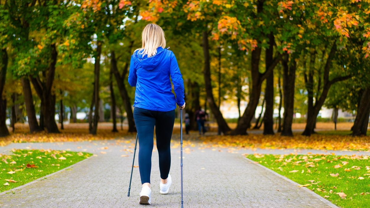 Middle aged woman exercising Nordic walking in city park
