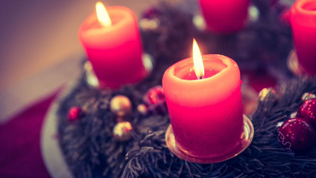 Close up of advent wreath with red lights and flame, fir branches