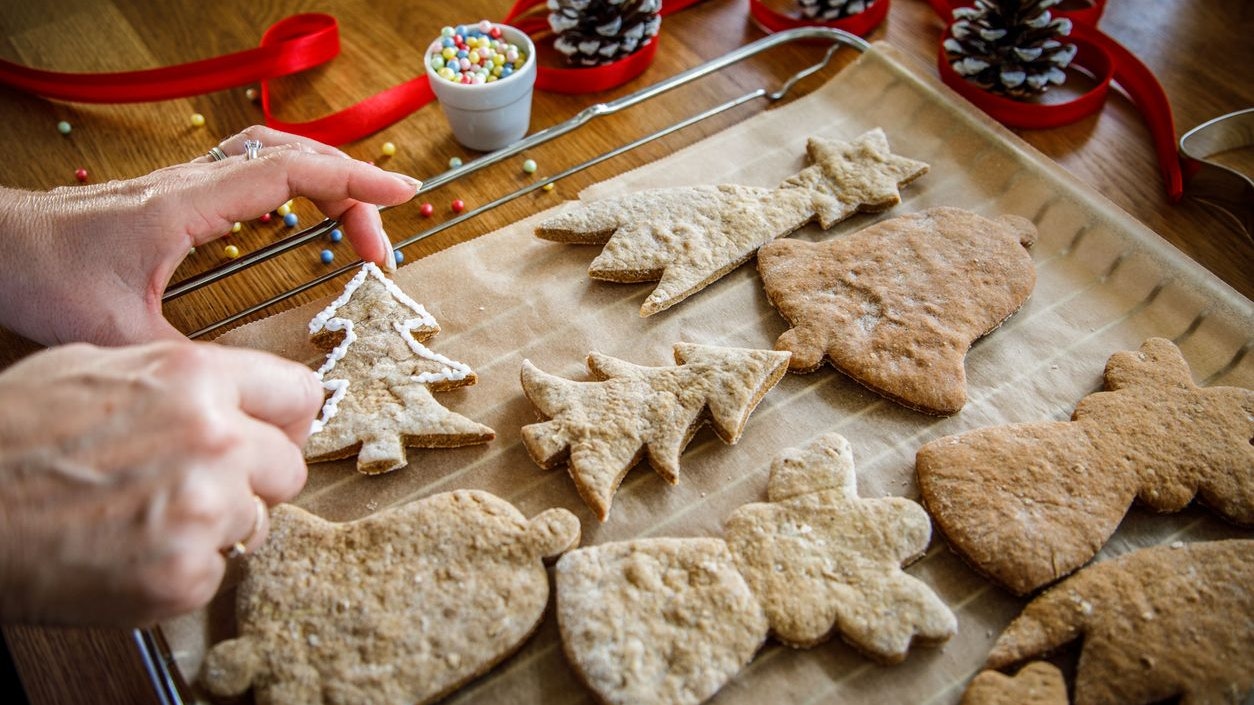 Woman making Christmas gingerbread cookies in kitchen