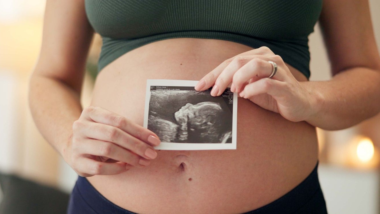 Hands, house and pregnant woman with ultrasound, maternity and wellness in living room. Closeup, pregnancy and girl with baby scan, apartment and excited for future, growth and prenatal with sonogram