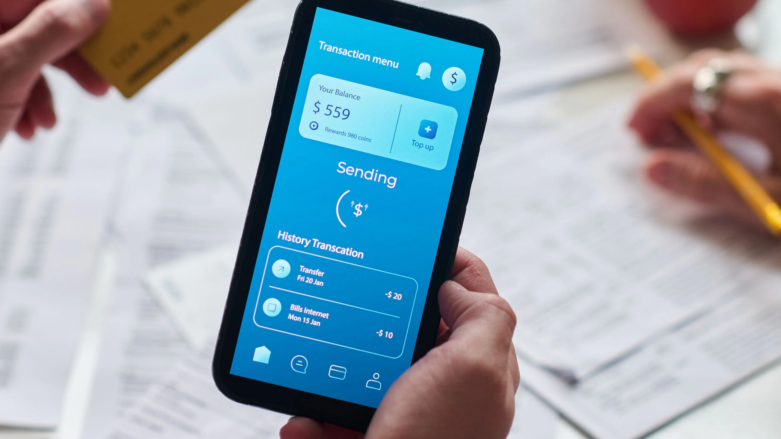 Caucasian young adult man holding smartphone displaying banking app while making online payment with credit card, sitting at table with financial documents and discussing taxes with woman