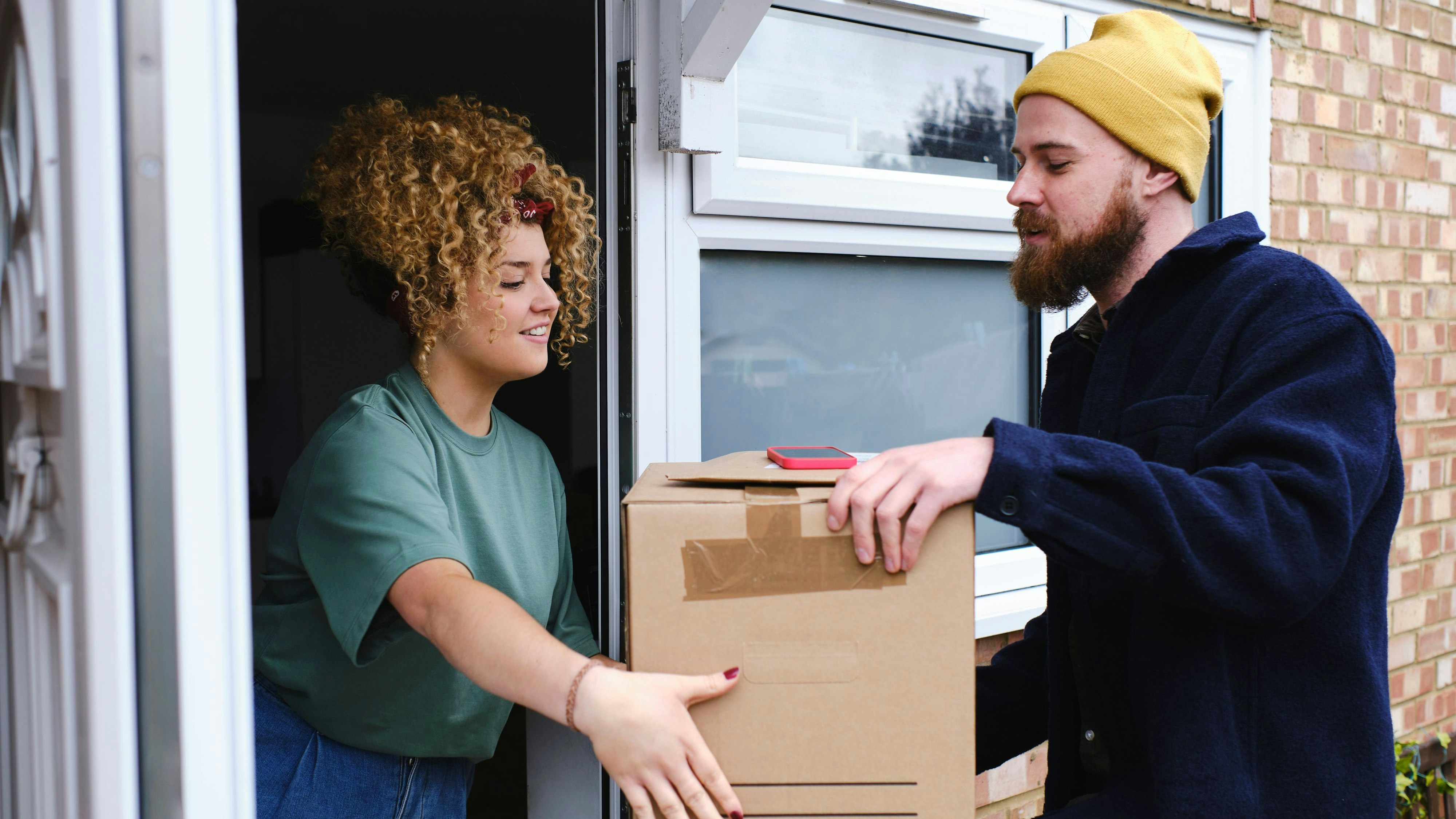 Happy young woman receiving boxes from delivery person